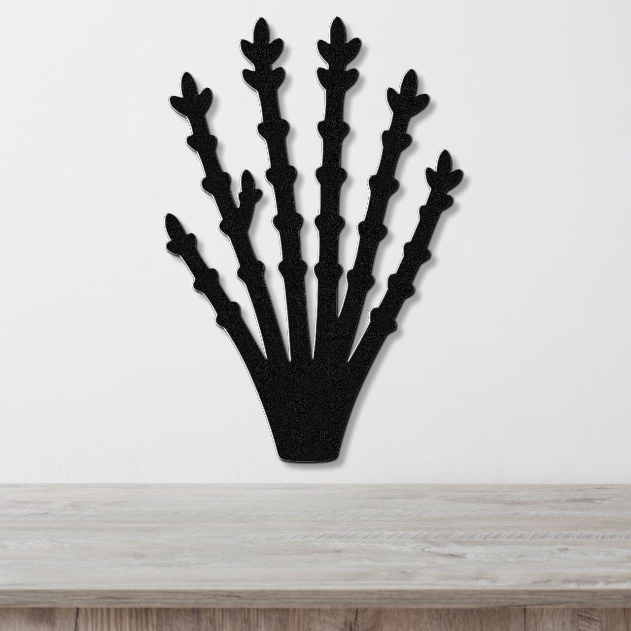 Black metal ocotillo wall art with branching cutouts, mounted on a white wall above a light wood surface.
