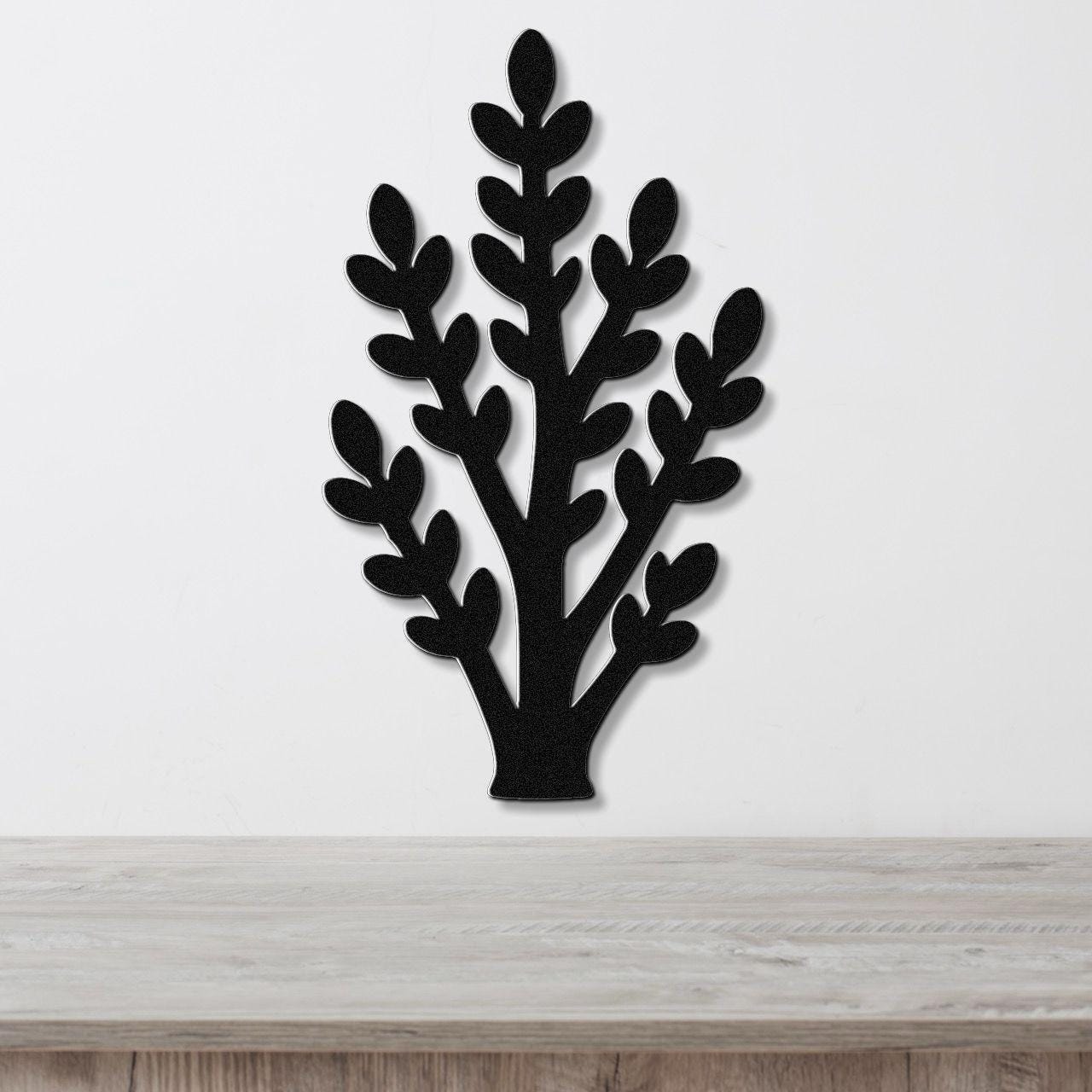 Black metal wall art in a jade plant silhouette with layered leaf cutouts, mounted on a white wall above a light wood surface.