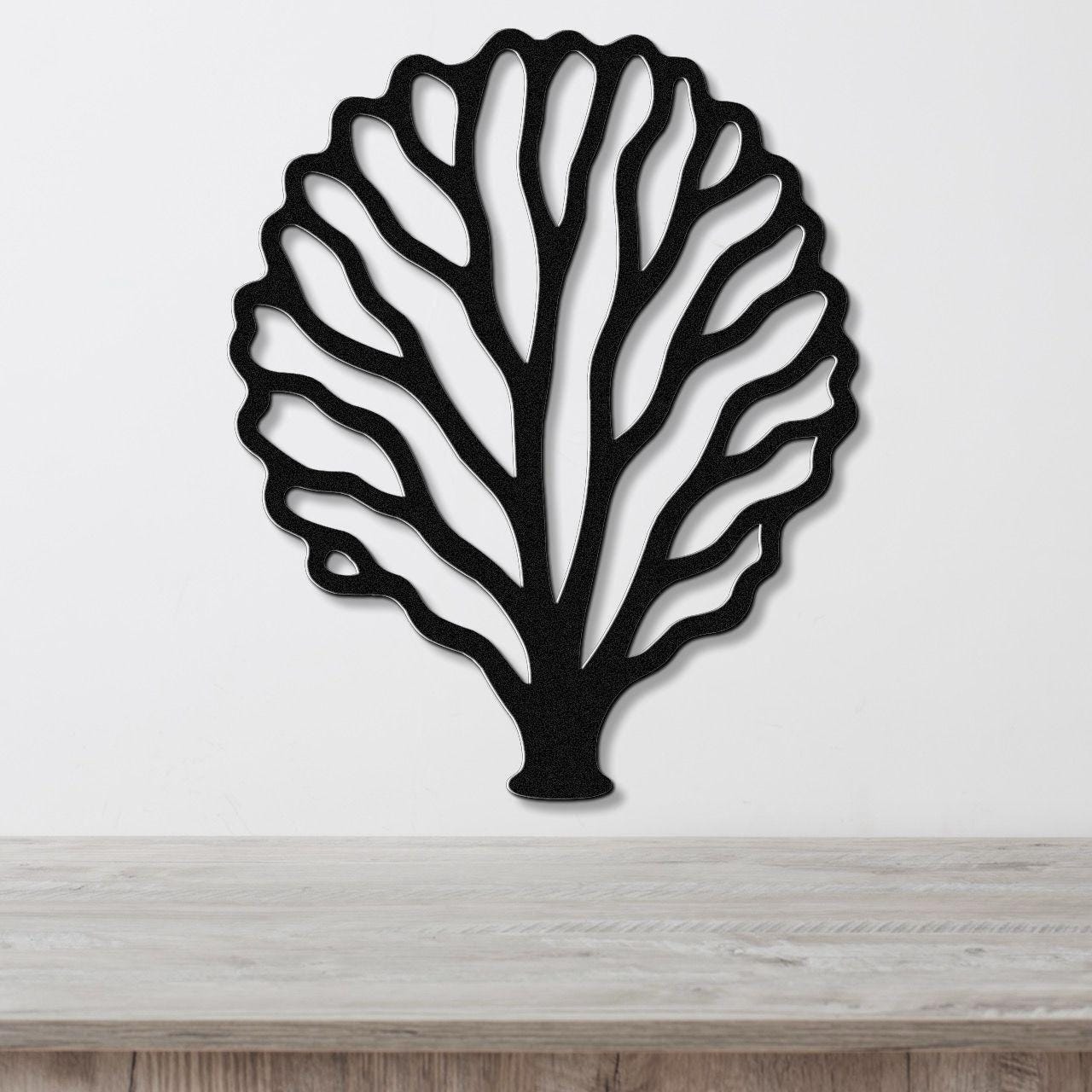 Black metal fan coral wall art with intricate cutout branches, mounted on a white wall above a light wood counter.