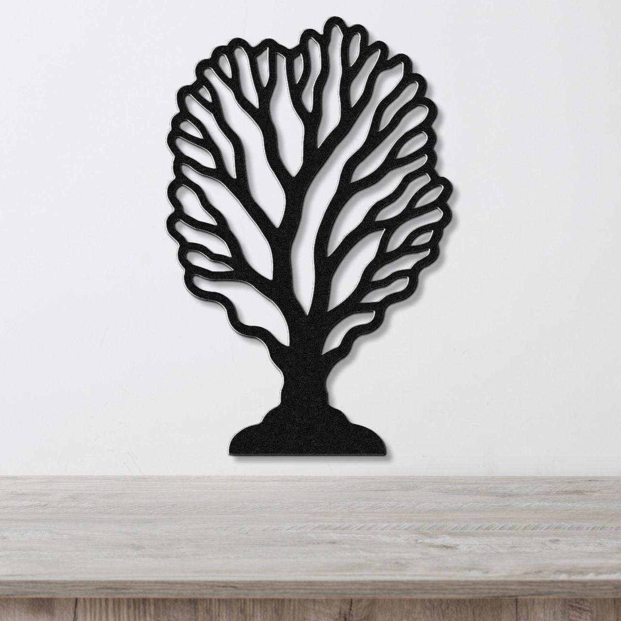 Black metal wall art cutout of a fan coral design, mounted on a white wall above a light wood surface.