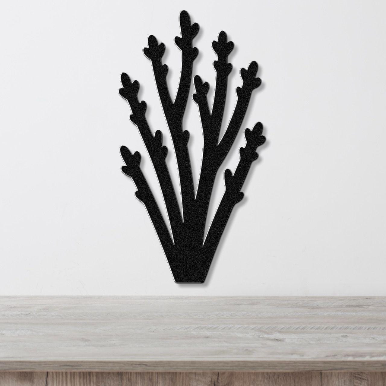 Black metal wall art in a silhouette of desert branches with multiple upward-reaching limbs, mounted on a white wall above a light wood surface.