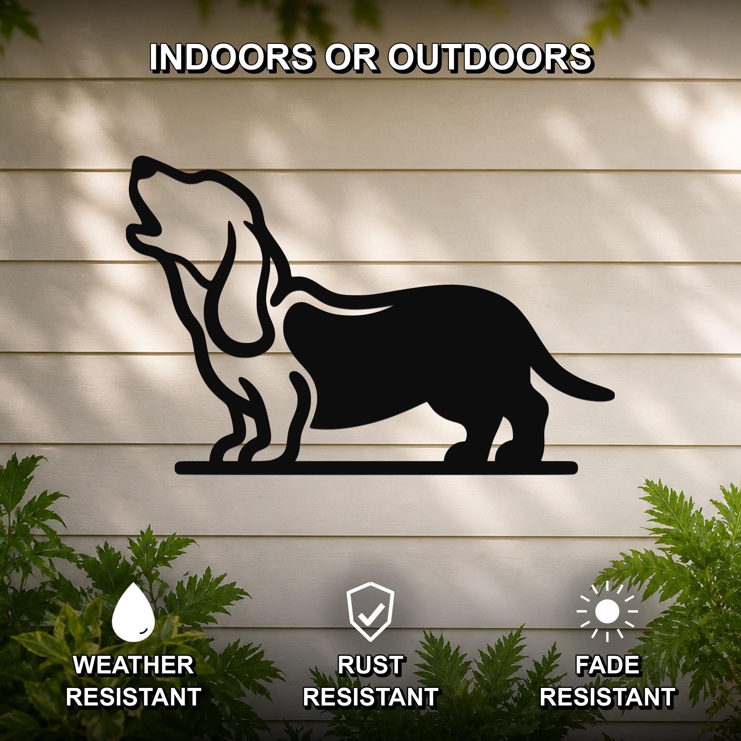 Black metal wall art silhouette of a howling basset hound, mounted on a light-colored outdoor wall with greenery below.