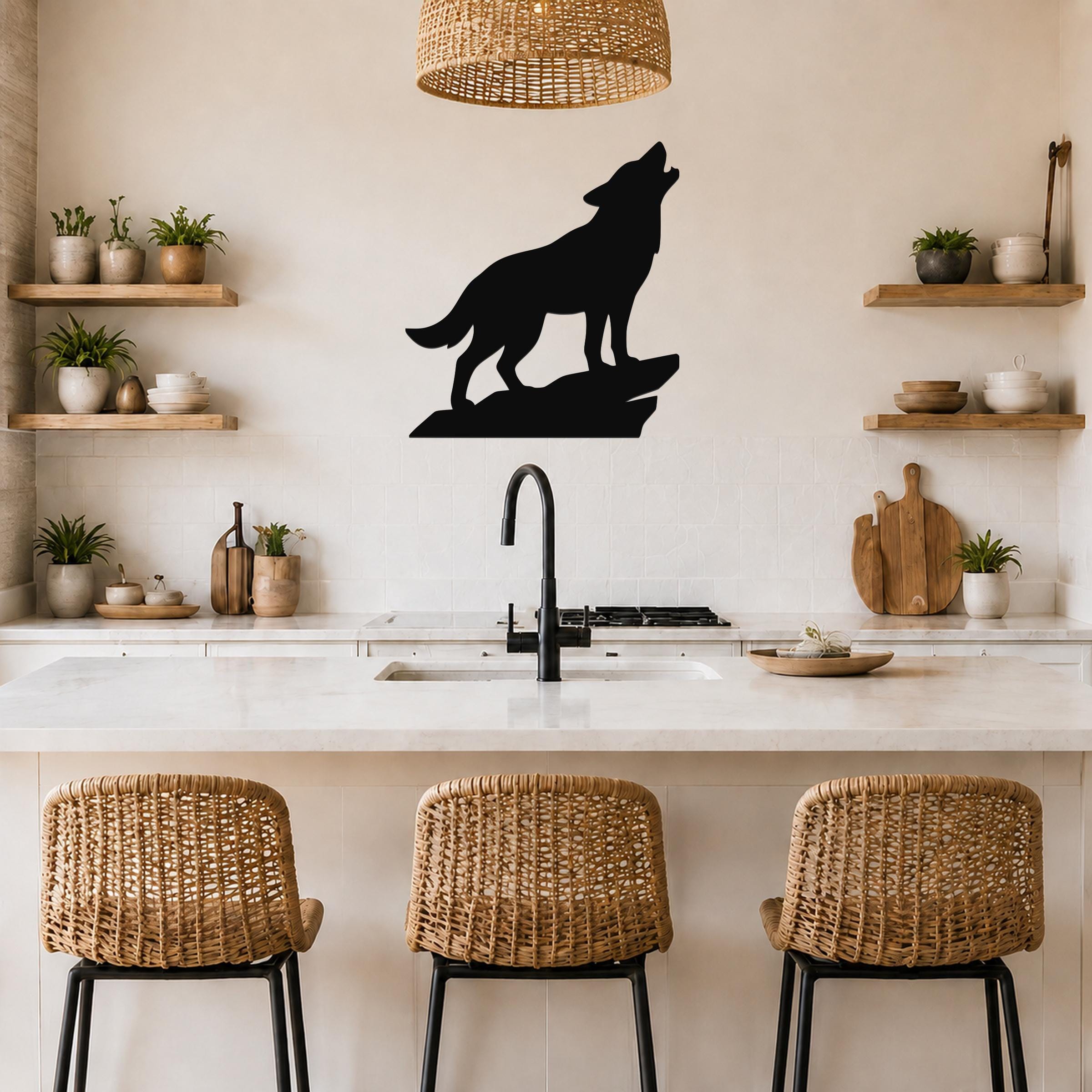 Black metal coyote wall art silhouette howling on a rock, mounted above a kitchen counter with wicker bar stools and open shelves.