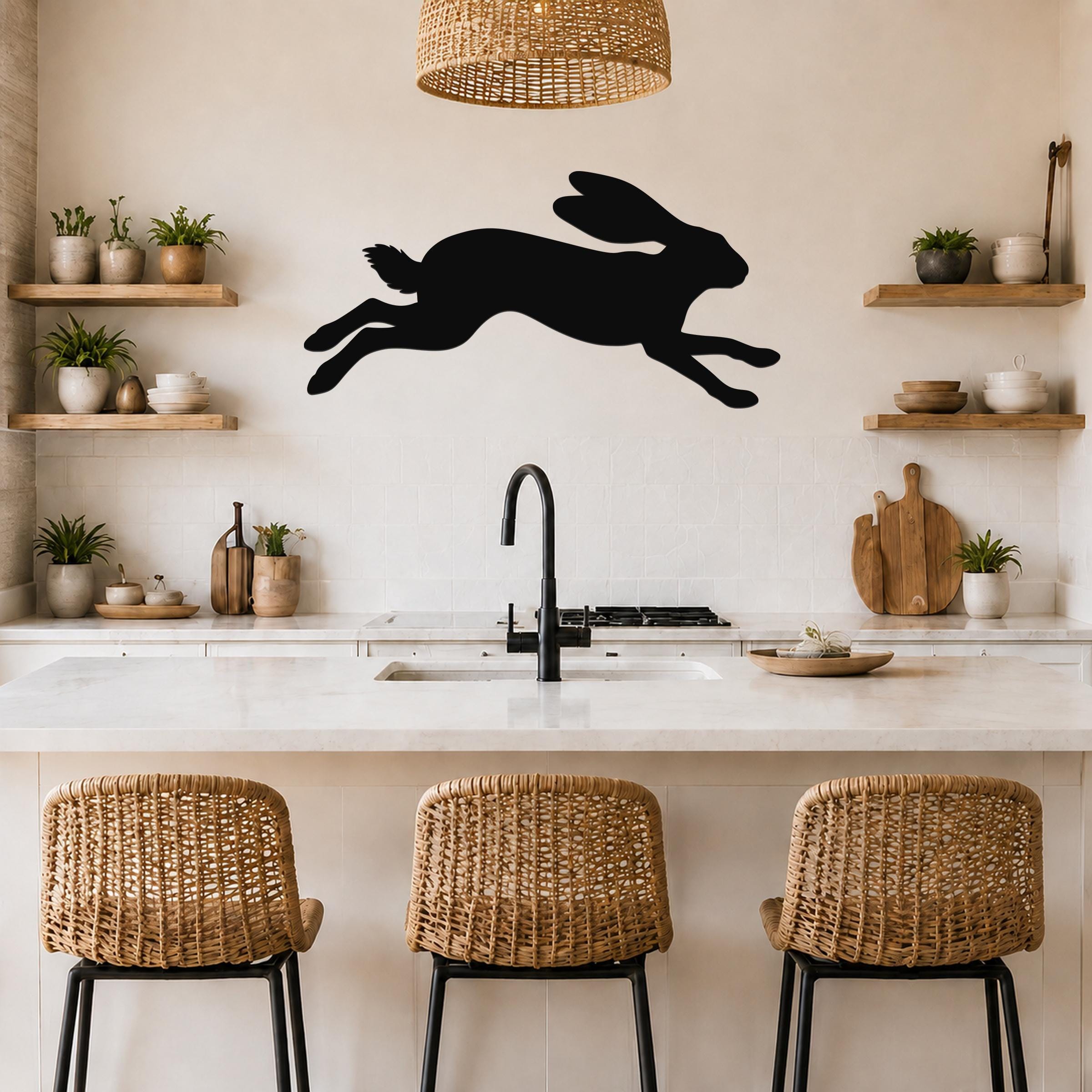 Black metal jackrabbit wall art silhouette with motion lines, mounted above a kitchen counter with wicker stools and wooden shelves.