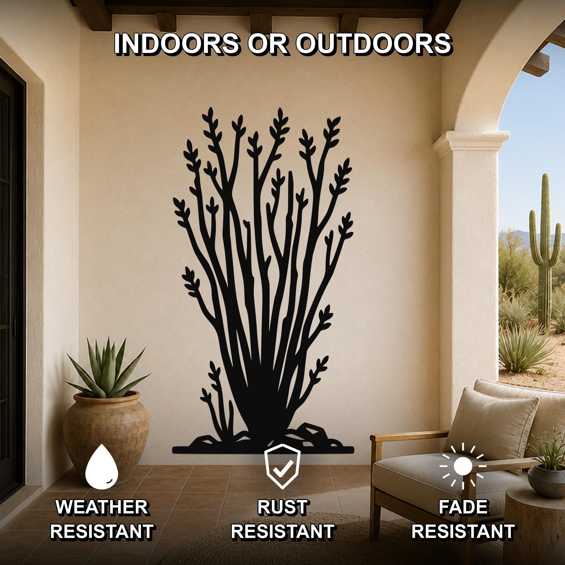 Black metal ocotillo wall art with branching cutouts, mounted on a beige patio wall above a chair, shown in an indoor-outdoor setting.