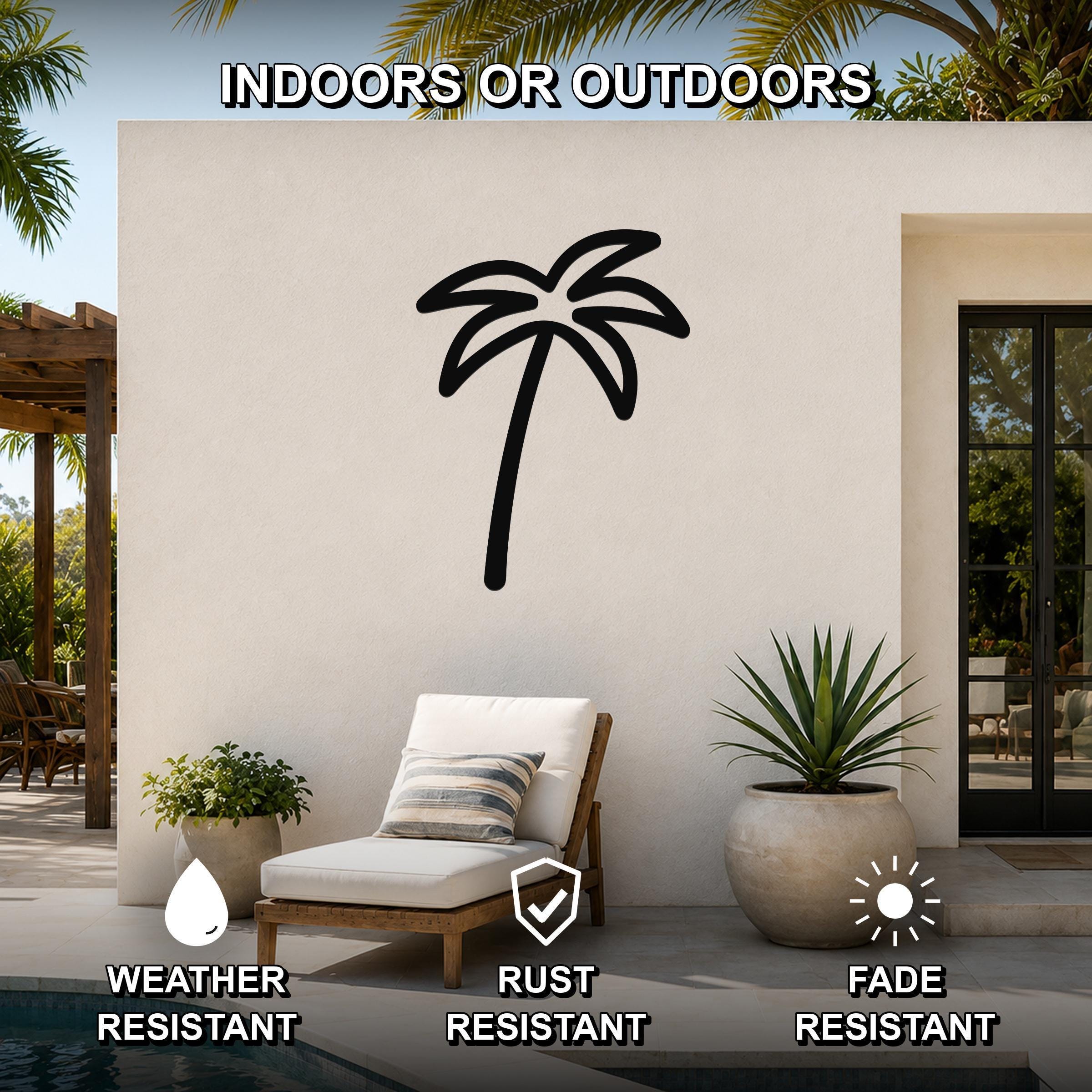 Black metal palm tree wall art silhouette mounted on an outdoor patio wall above a lounge chair, with visible weather, rust, and fade resistance icons.