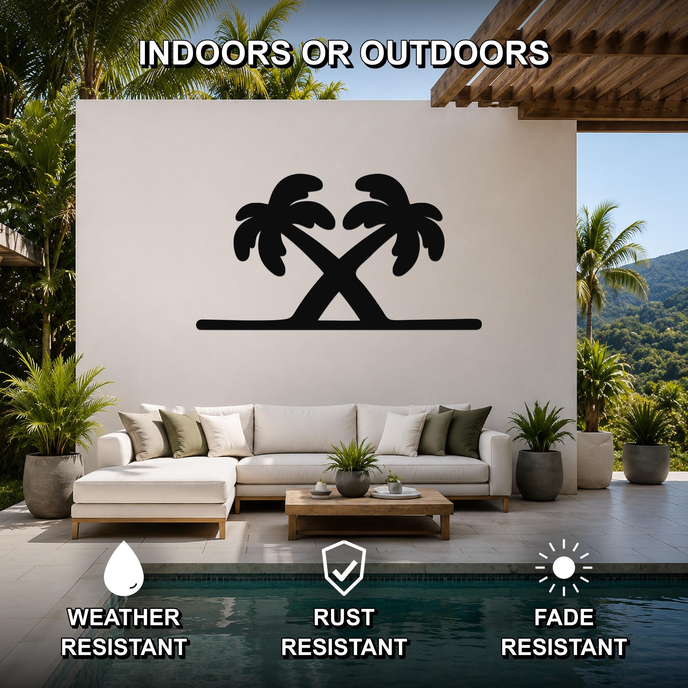 Black metal palm tree wall art with two crossed silhouettes, mounted on a white outdoor wall above a sofa in a patio living area.