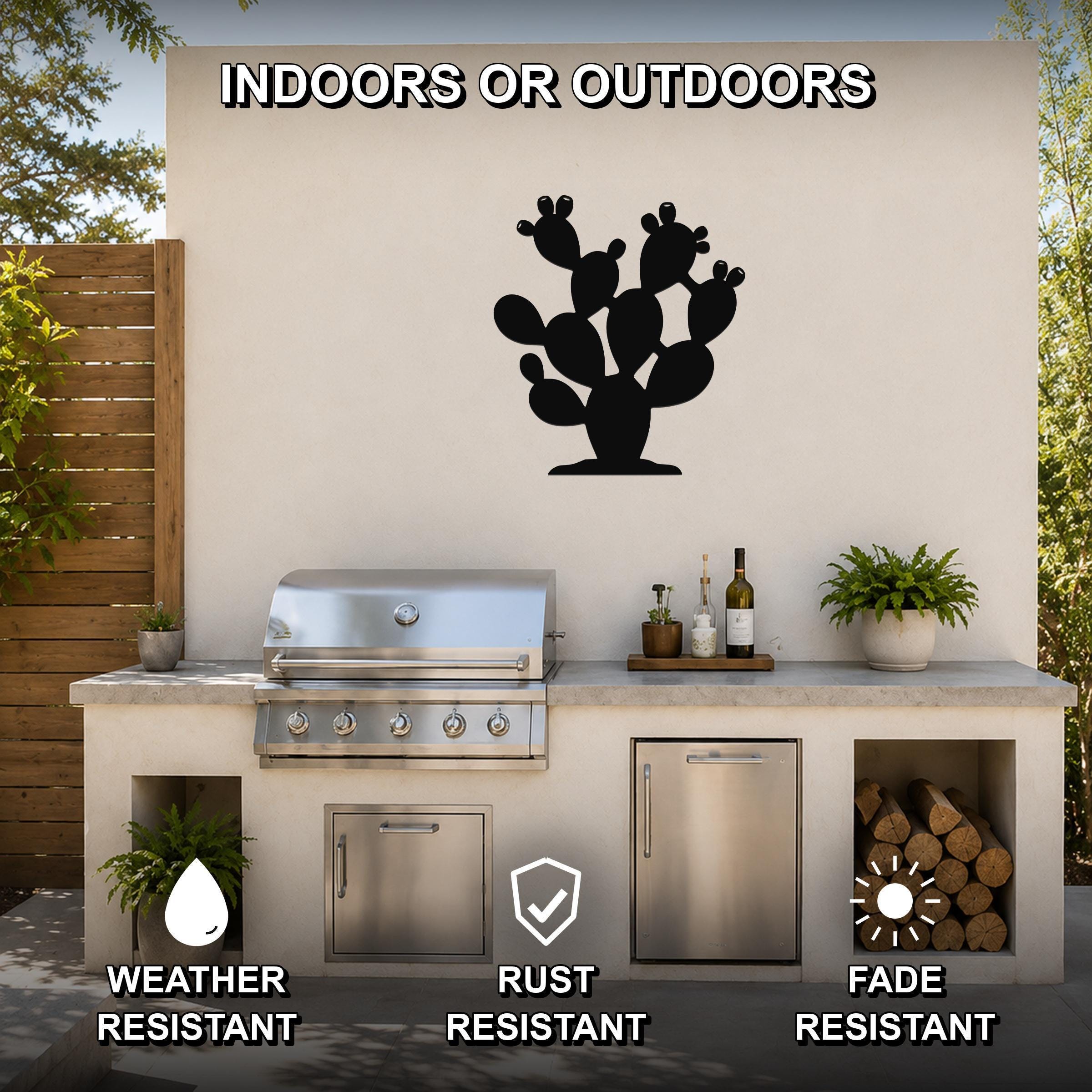 Black metal prickly pear cactus wall art with cutout details, mounted on an outdoor kitchen wall above a stainless steel grill.