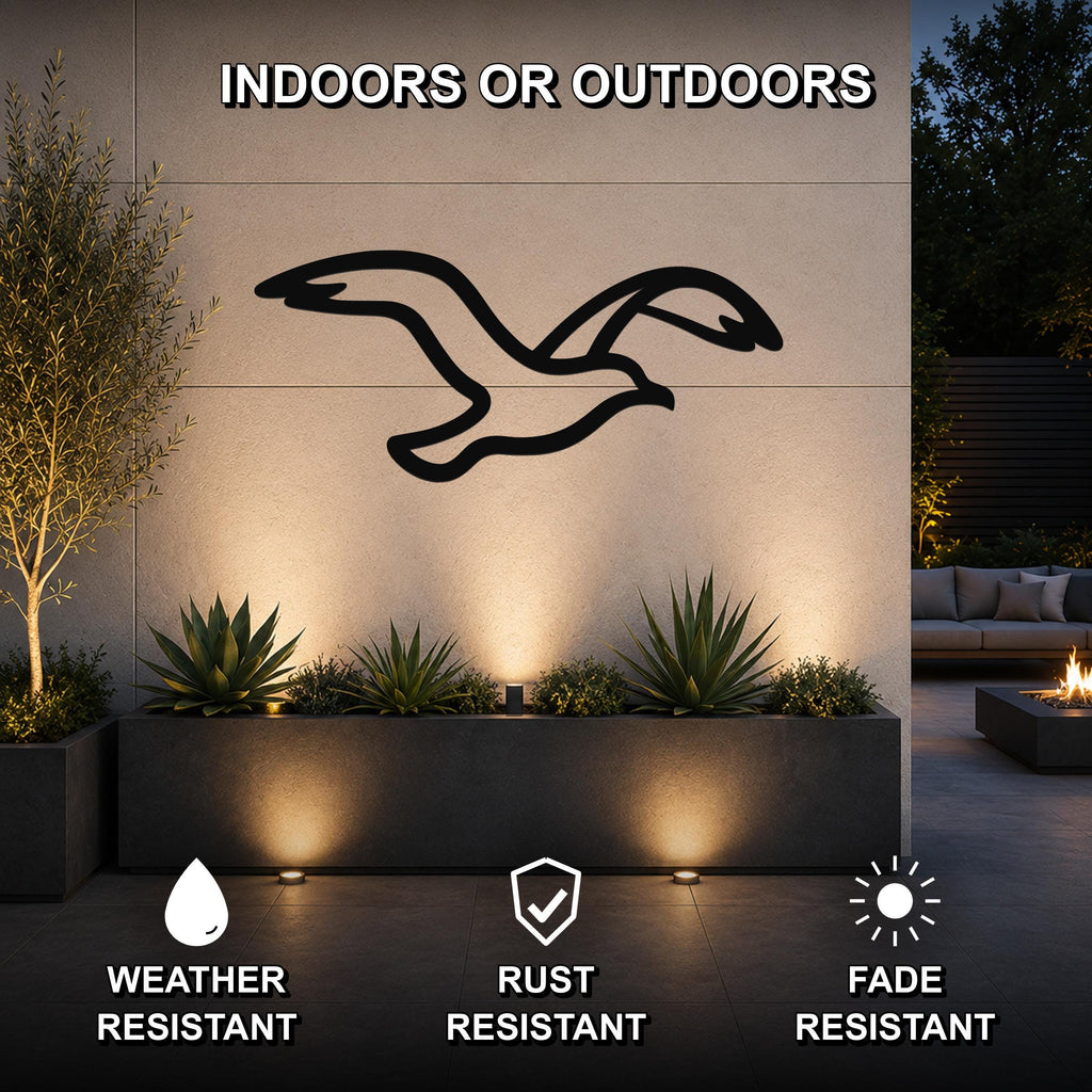 Black metal seagull wall art silhouette mounted on an outdoor wall above a planter, with text indicating it is weather, rust, and fade resistant for indoor or outdoor use.