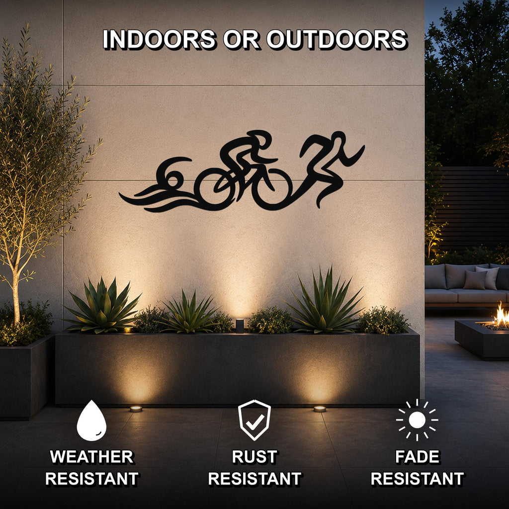 Black metal triathlon wall art with cyclist and runner silhouettes and motion lines, mounted on an outdoor wall above a planter in a modern patio setting.
