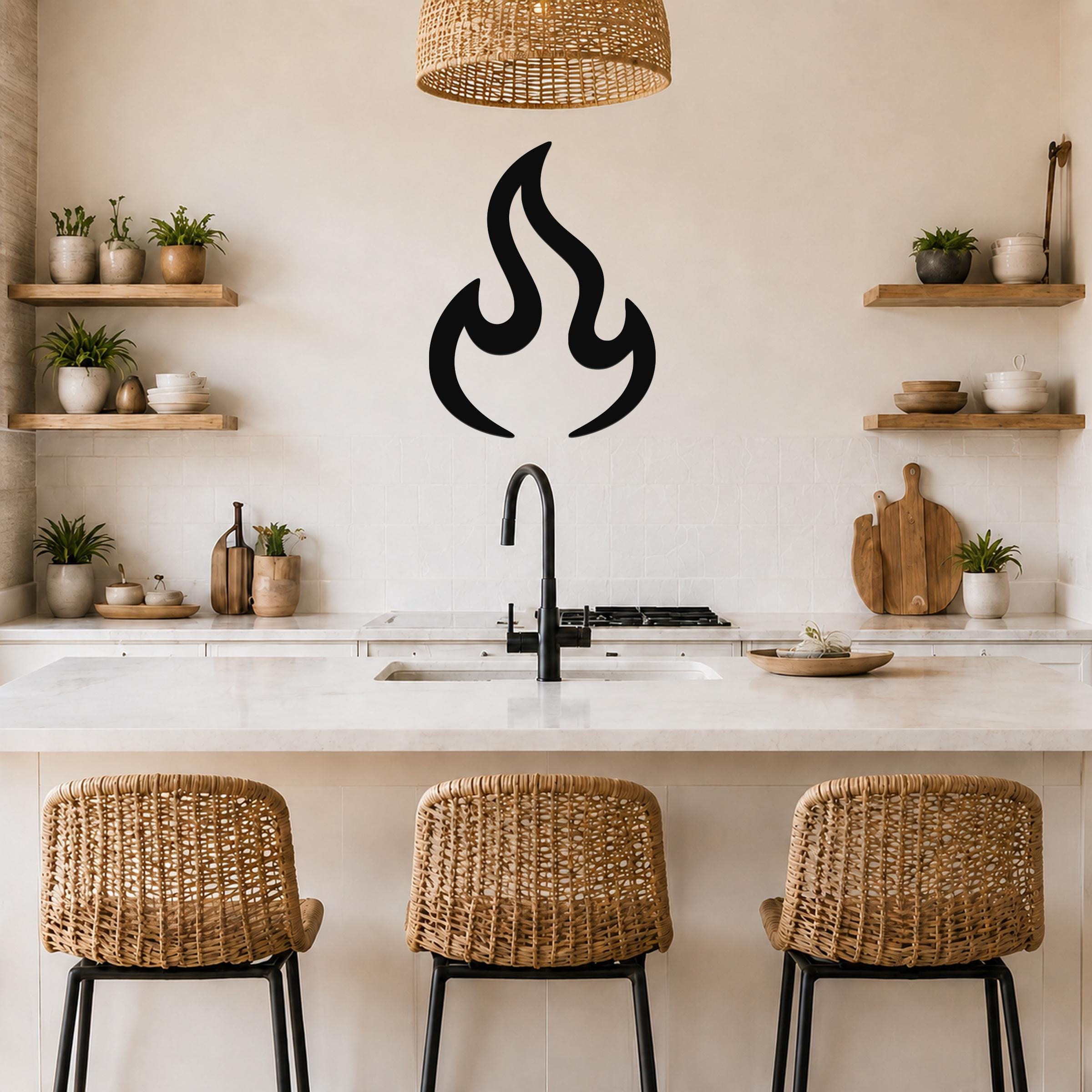 Black metal flame wall art with a bold silhouette design, mounted on a kitchen wall above a counter with a sink and wicker bar stools.