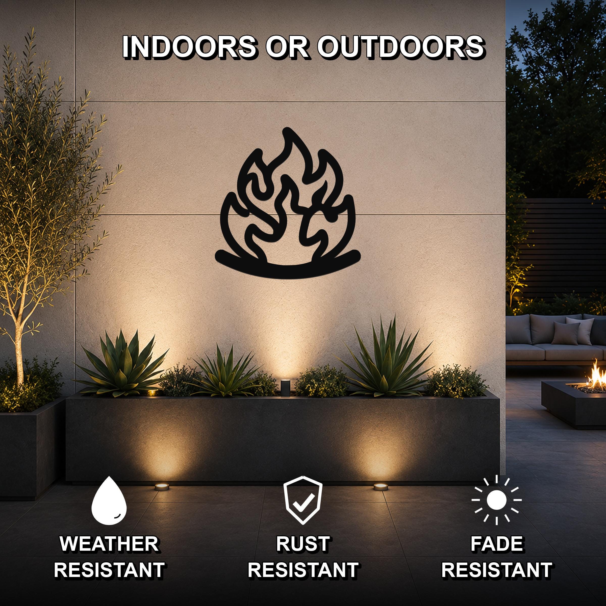 Black metal flame wall art with fluid motion cutouts, mounted on an outdoor wall above a planter in a modern patio setting.