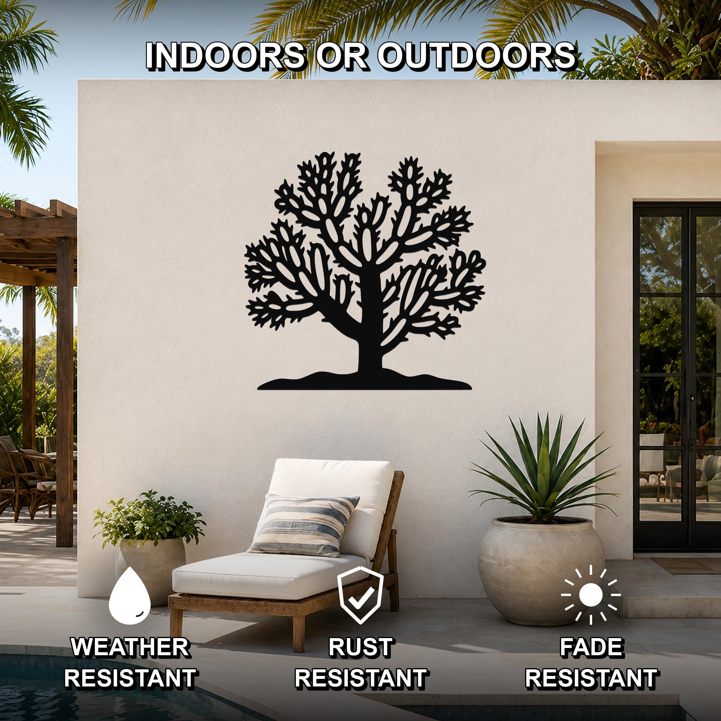 Black metal Cholla cactus wall art with intricate branch cutouts, mounted on an outdoor patio wall above a lounge chair.