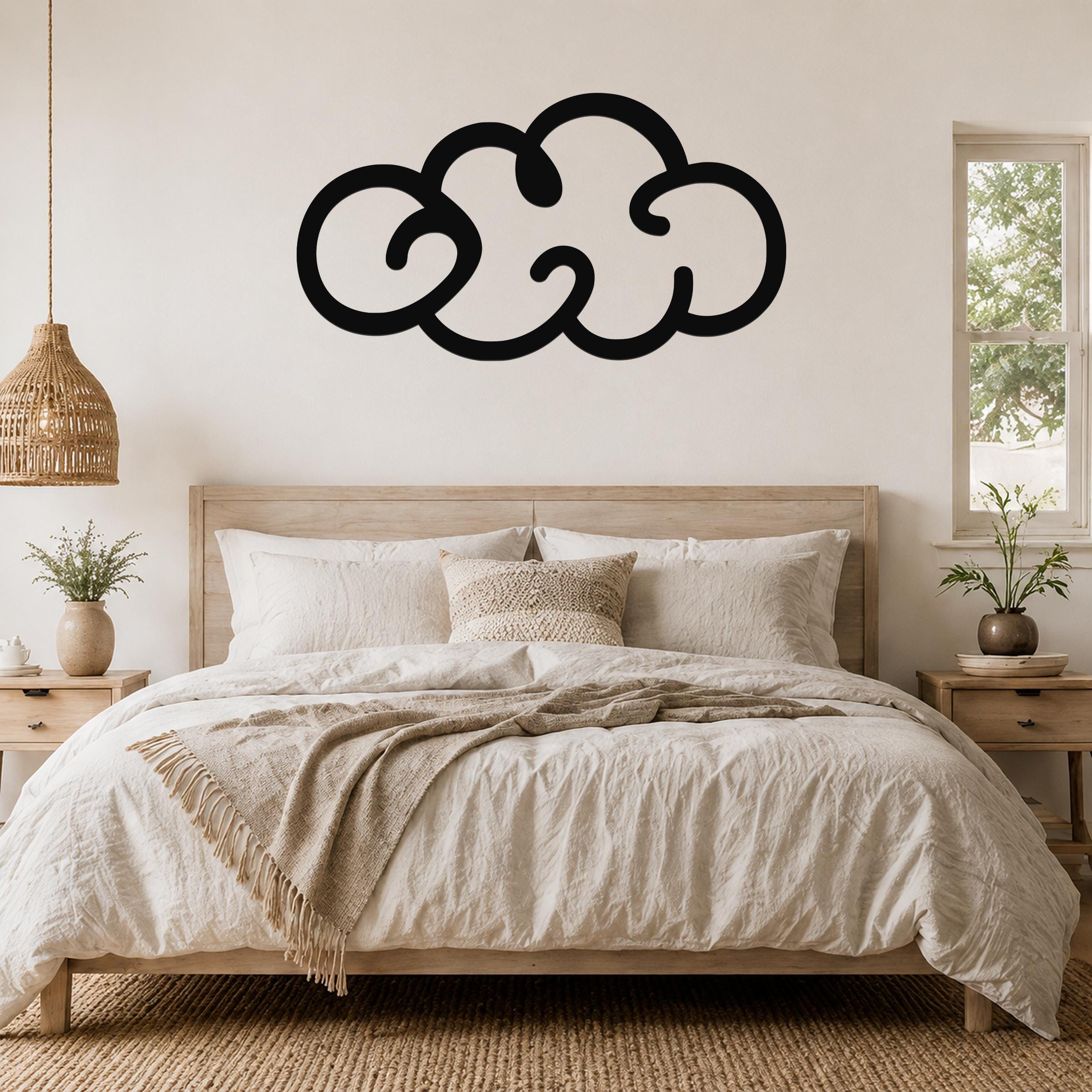 Black metal cloud wall art with a bold silhouette design, mounted above a wooden bed in a neutral-toned bedroom.