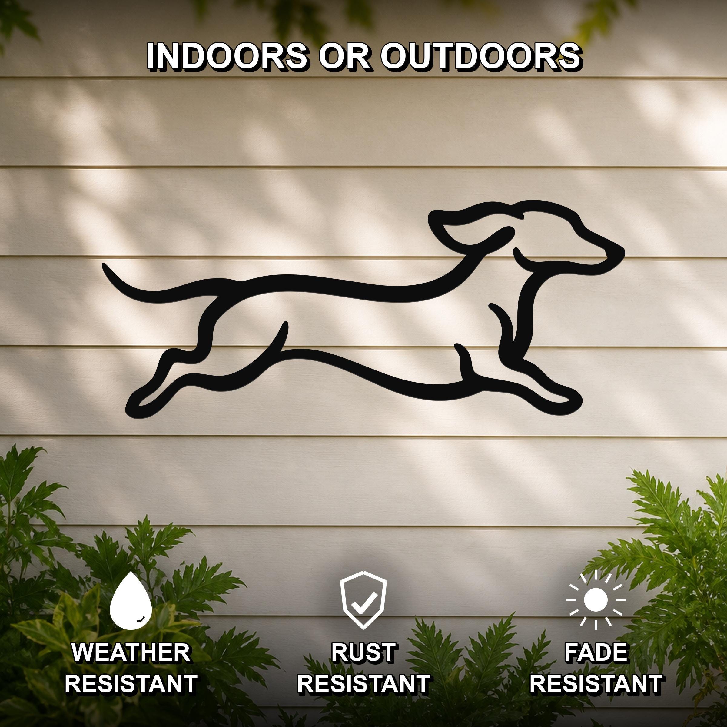 Black metal dachshund wall art with motion-line cutouts, mounted on a light-colored outdoor wall with greenery below.