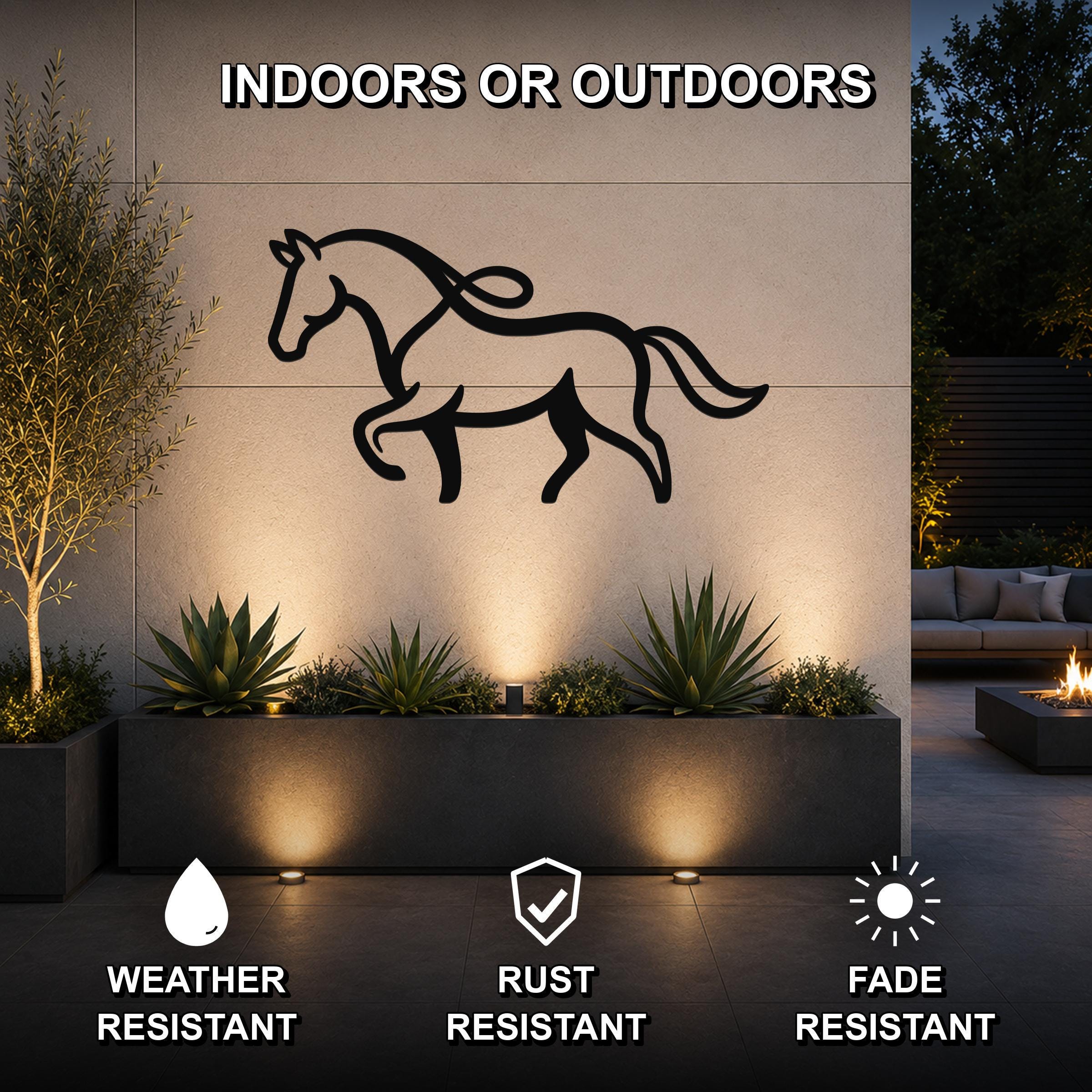 Black metal horse silhouette wall art with flowing mane and tail cutouts, mounted on an outdoor wall above a planter in a modern patio setting.