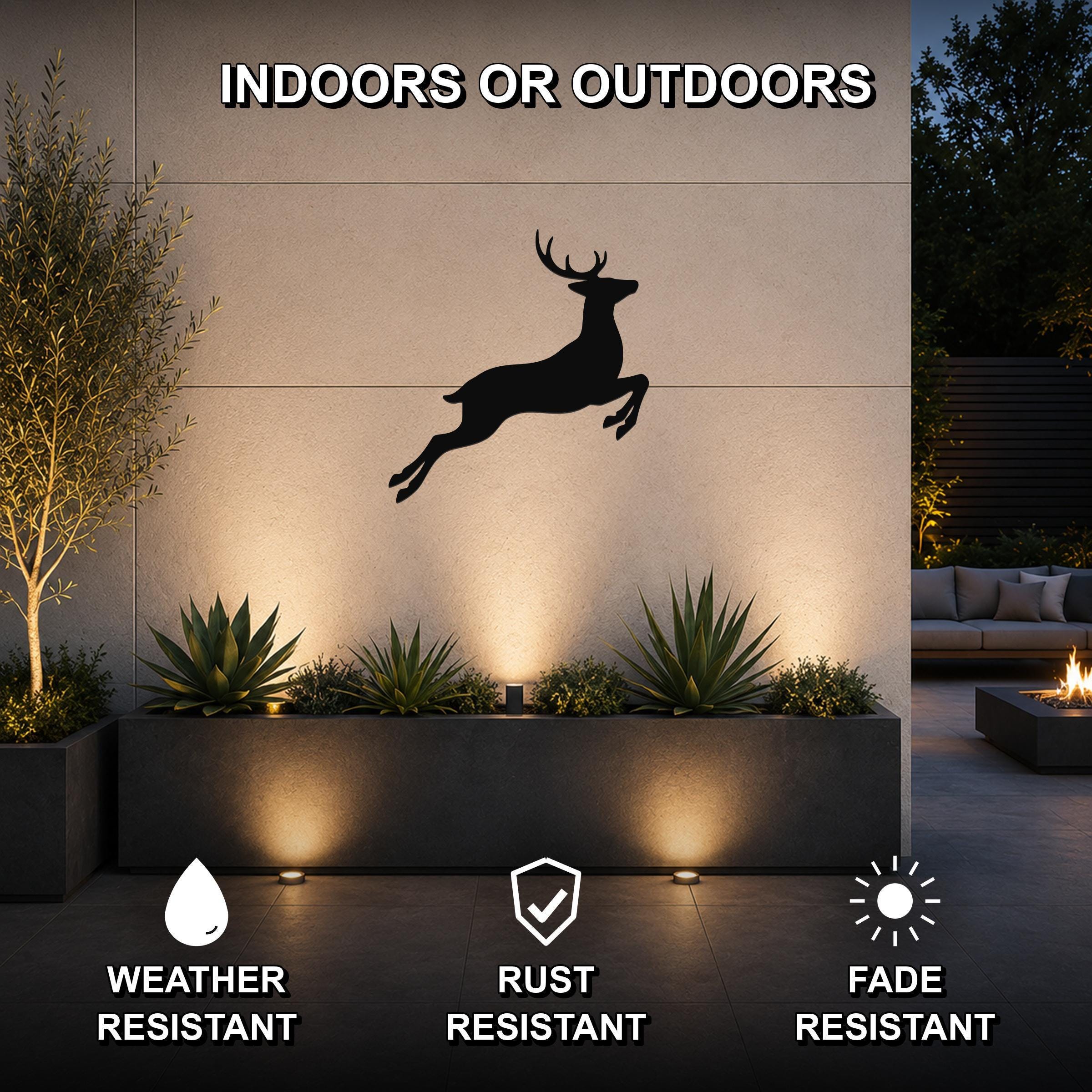 Black metal jumping deer wall art silhouette mounted on an outdoor wall above a planter, with text indicating it is weather, rust, and fade resistant for indoor or outdoor use.