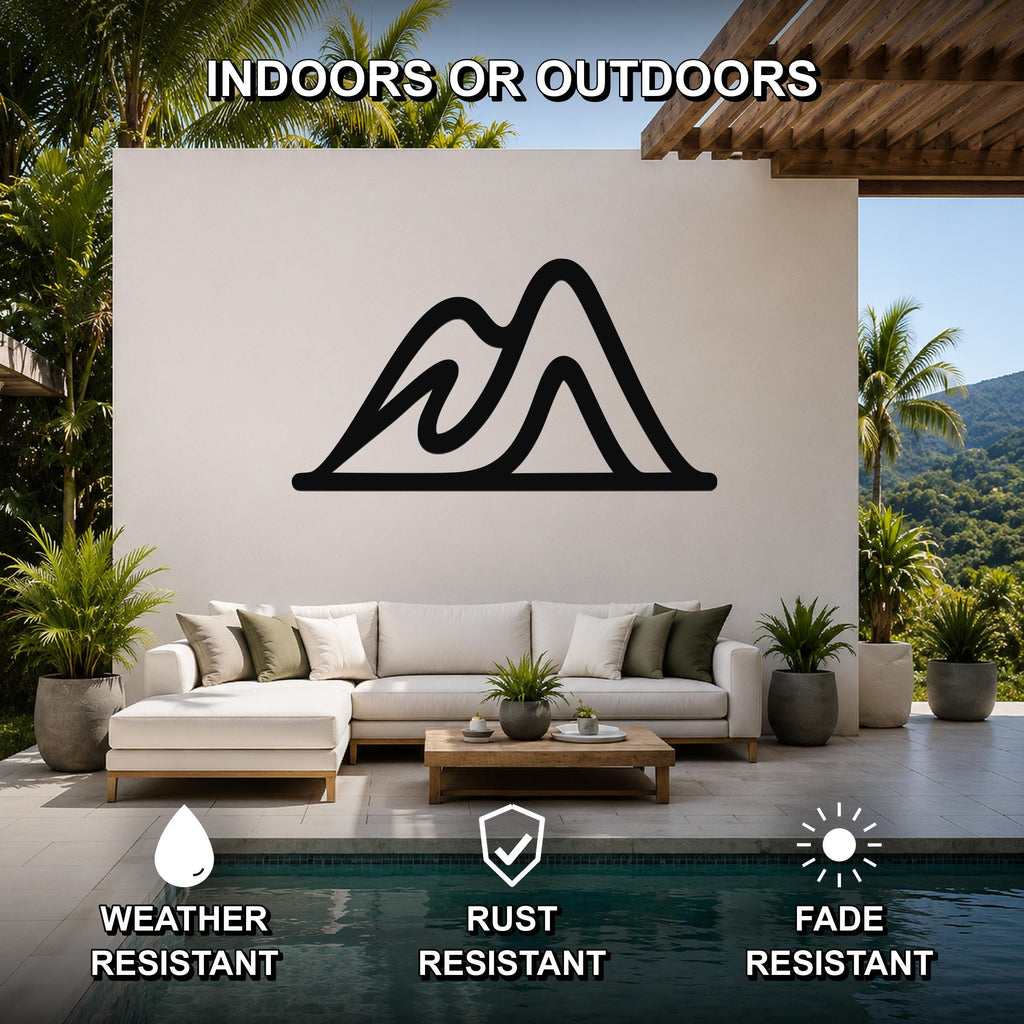 Black metal mountain silhouette wall art mounted on a white outdoor wall above a white sectional sofa in a patio living area.