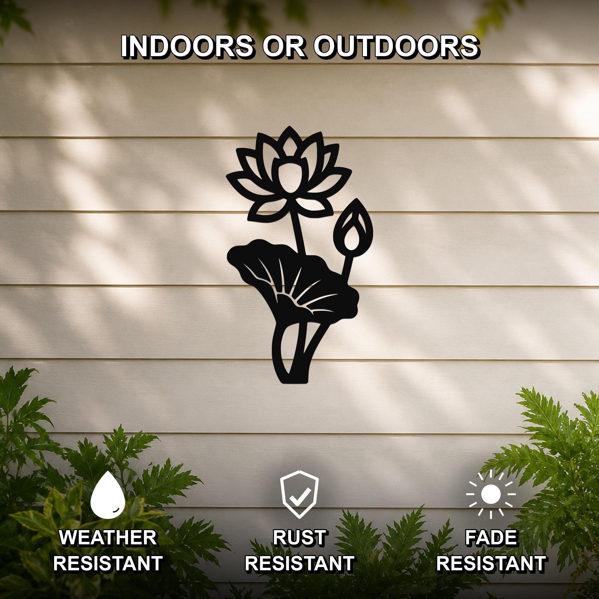 Black metal lotus flower wall art with a cutout design, mounted on a beige outdoor wall with greenery, weather resistant, rust resistant, and fade resistant.
