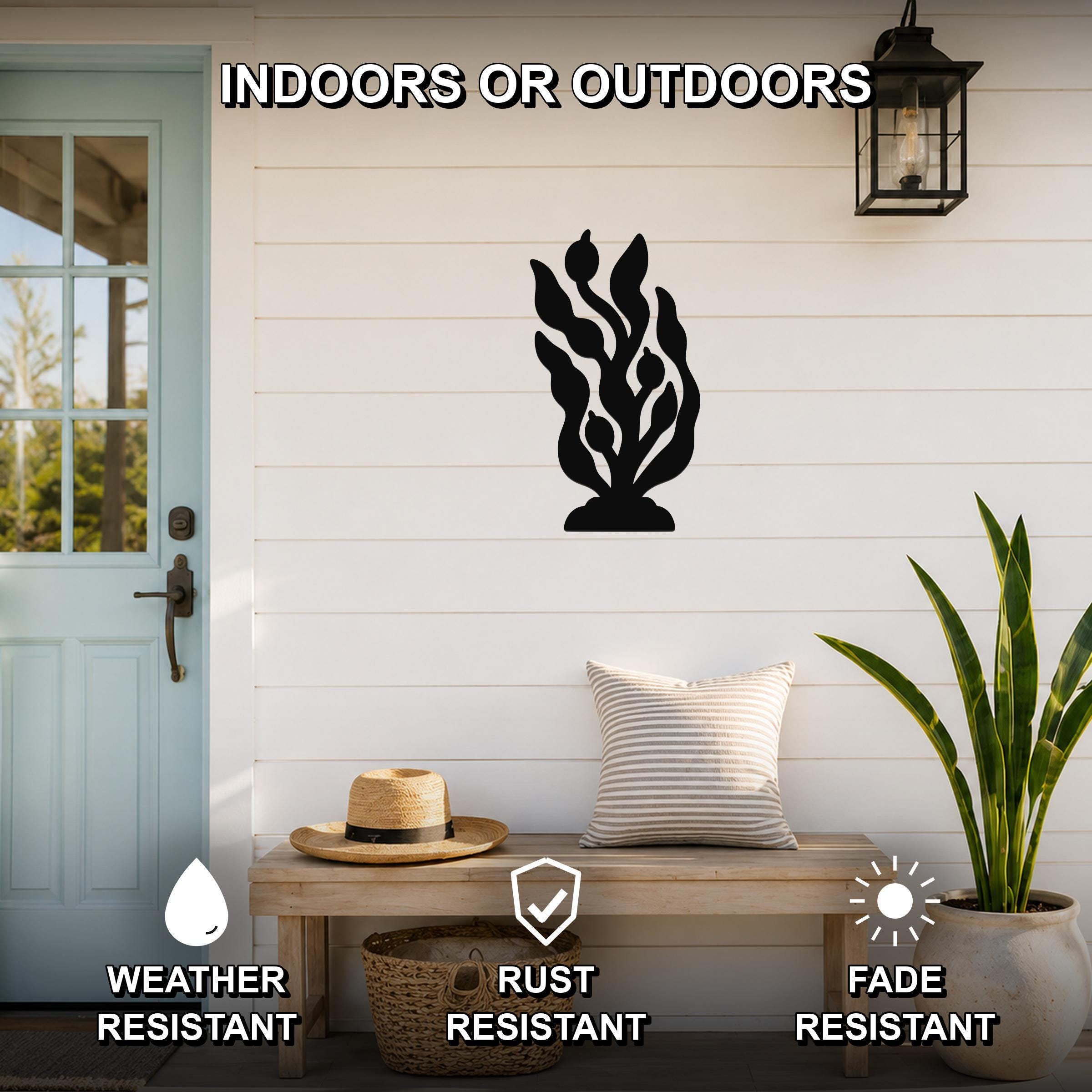 Black metal kelp and seaweed wall art silhouette mounted on a white shiplap wall above a wooden bench on a porch, with text indicating it is weather, rust, and fade resistant.