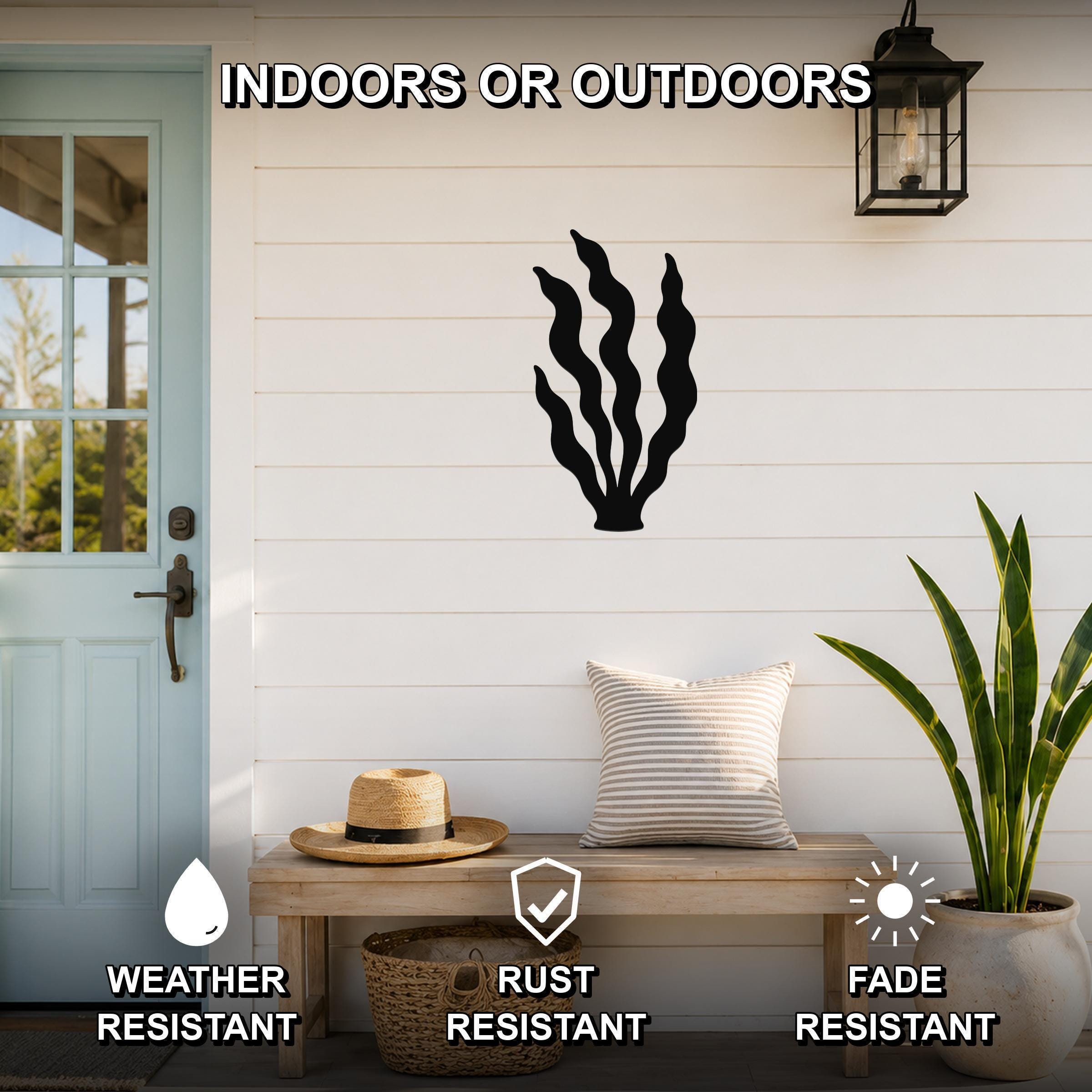Black metal kelp wall art with wavy blade cutouts, mounted on a white shiplap wall above a wooden bench in a coastal entryway.