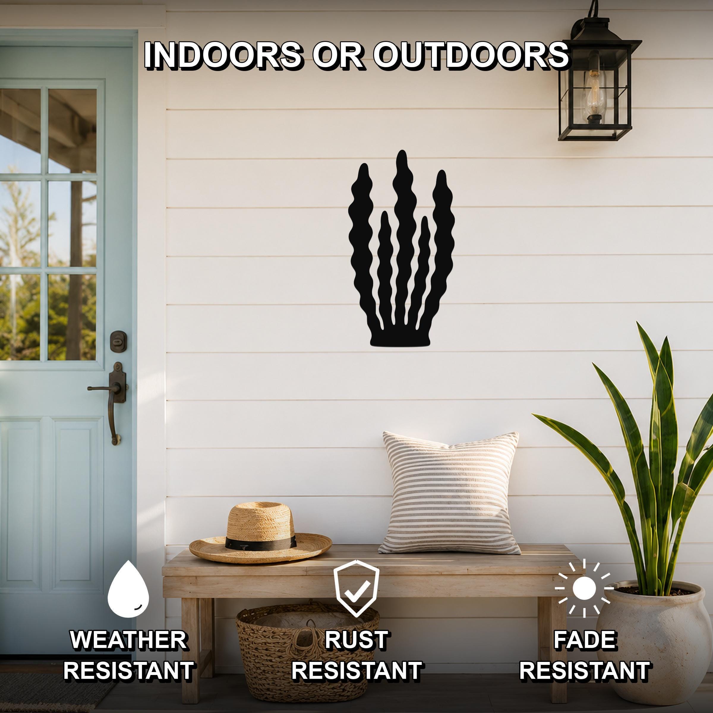 Black metal kelp wall art with wavy cutout design, mounted on a white shiplap wall above a wooden bench on a porch.