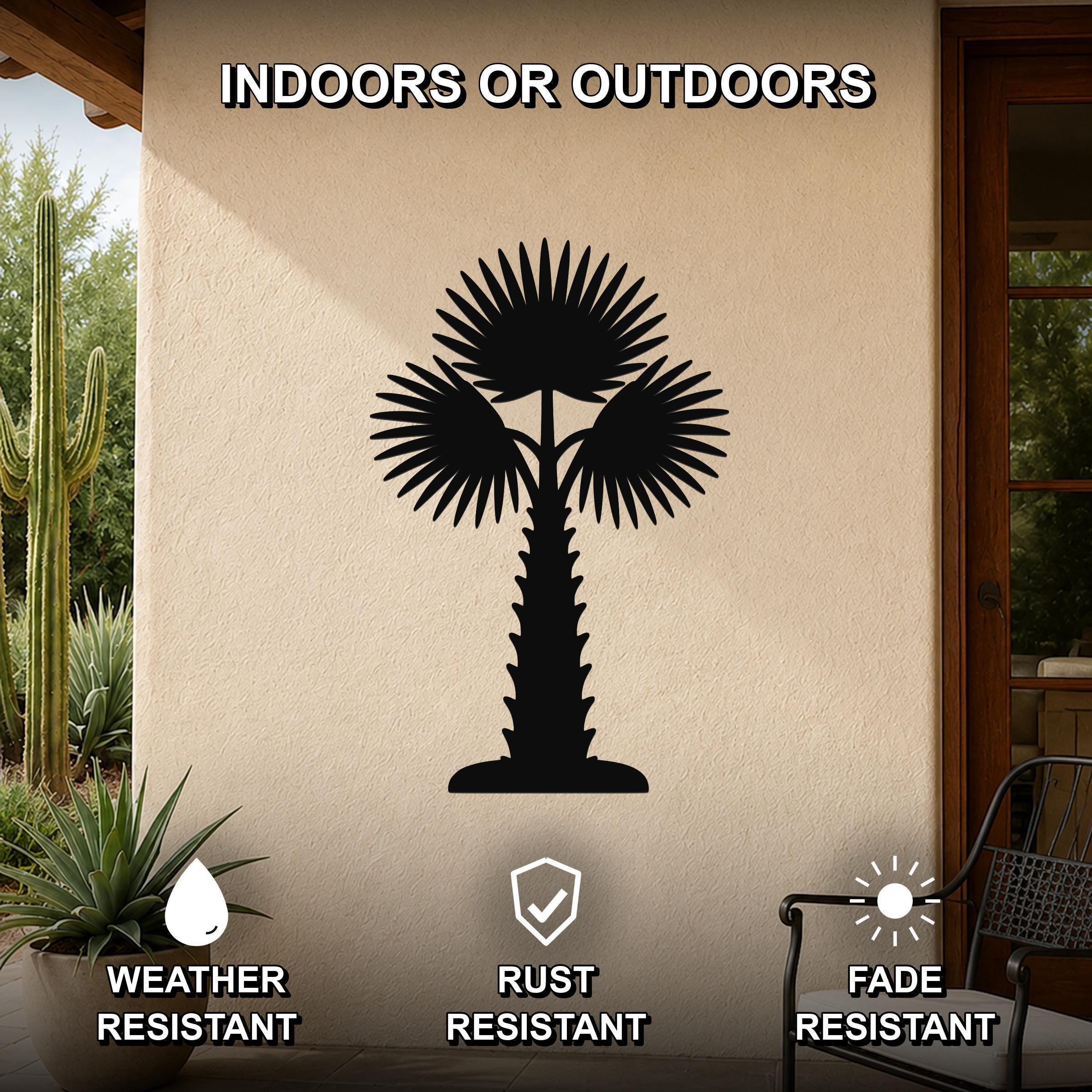 Black metal palm tree wall art with fan-shaped fronds and a textured trunk, mounted on an outdoor patio wall above a potted succulent.