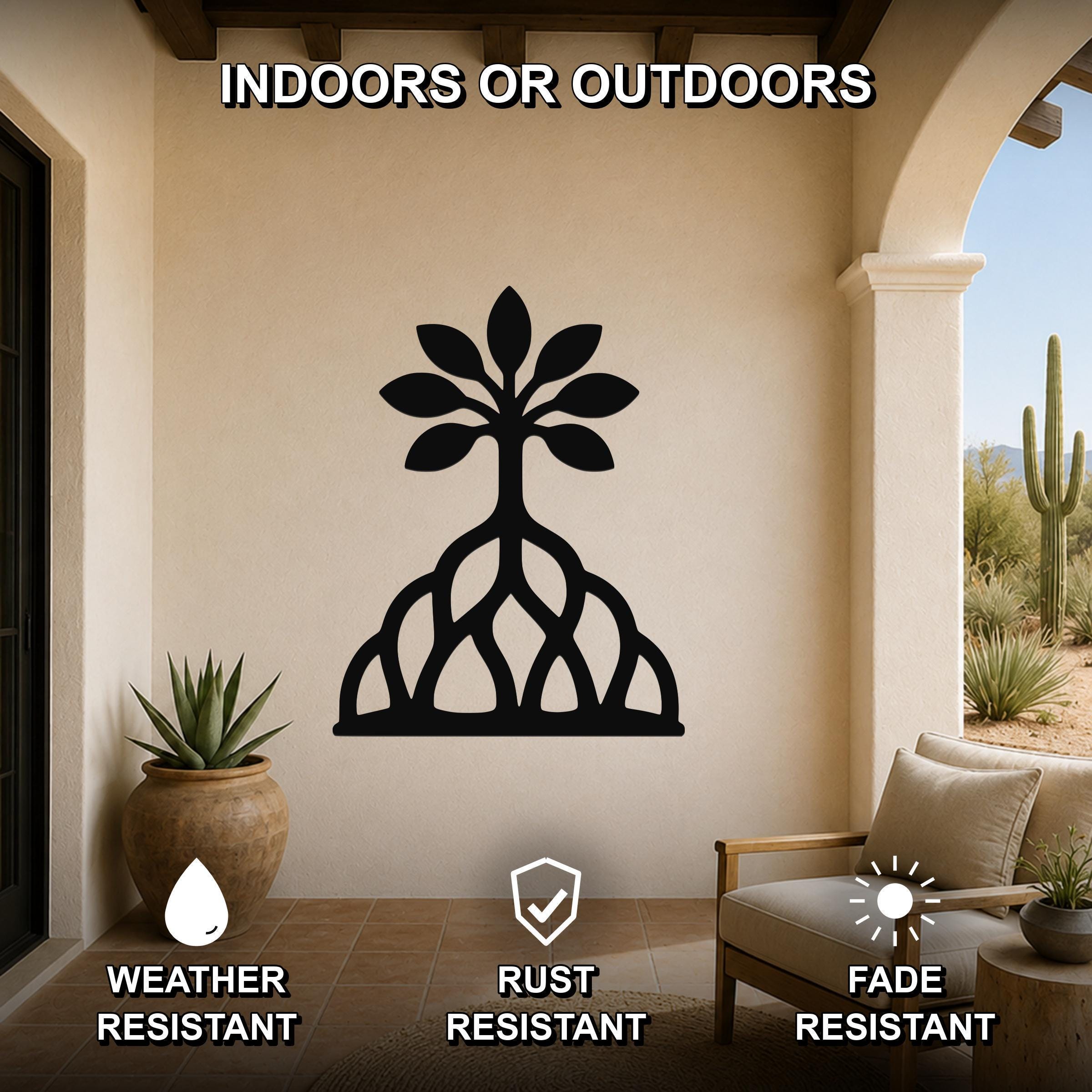 Black metal wall art in the shape of a tree with visible roots and leaf cutouts, mounted on a beige wall in a covered patio with outdoor furniture and potted plants.