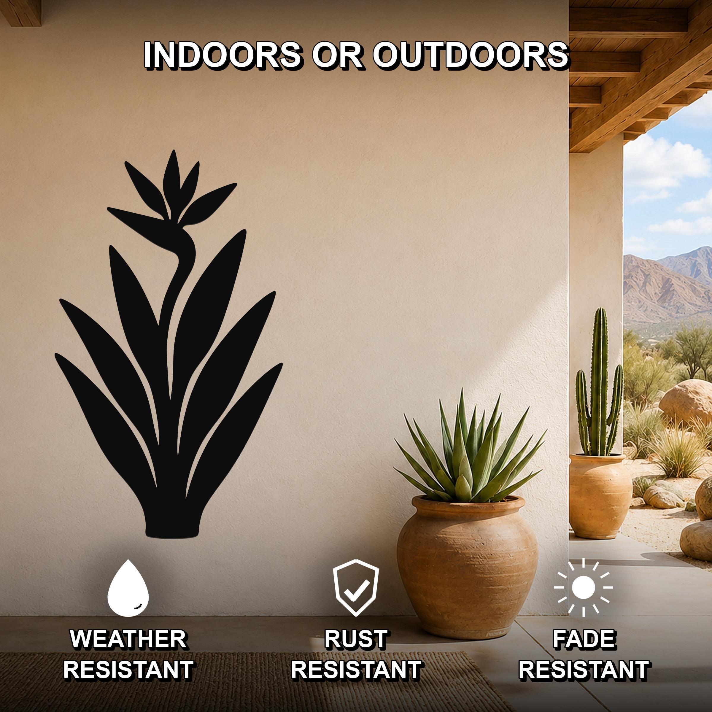 Black metal Bird of Paradise wall art silhouette mounted on a beige outdoor wall, displayed above a potted succulent on a patio with mountains in the background.