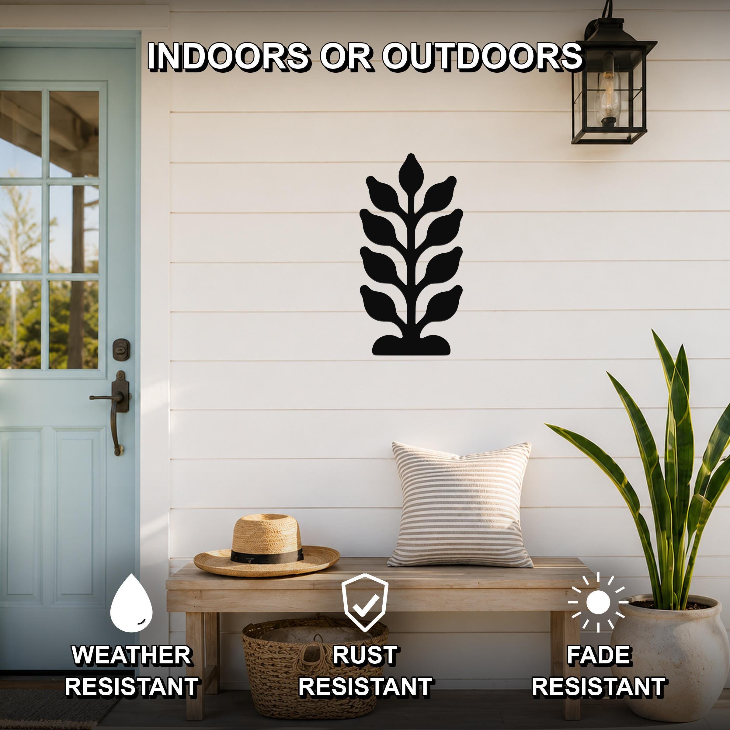 Black metal kelp wall art with leafy cutout design, mounted on a white shiplap wall above a wooden bench in a porch setting.