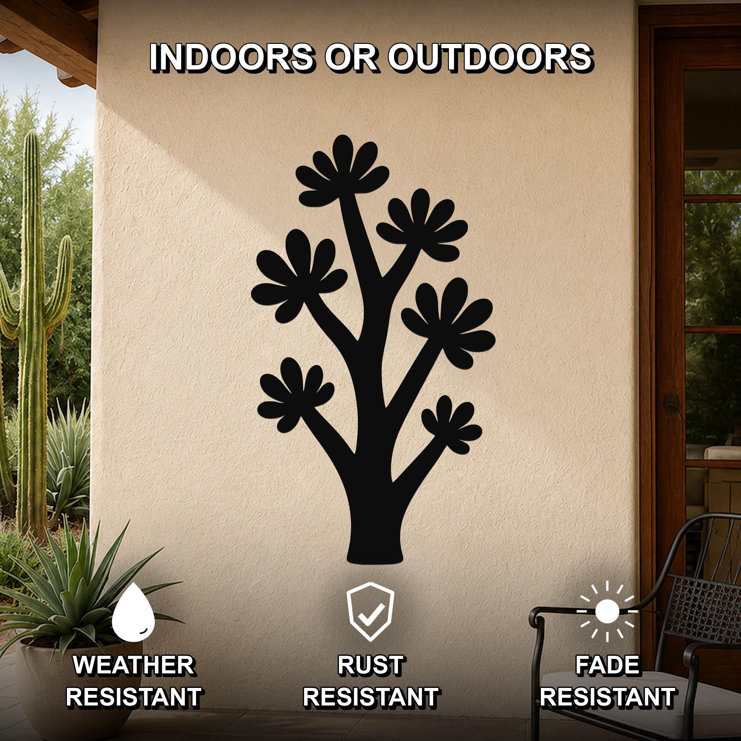 Black metal wall art in a tree silhouette with flower cutouts, mounted on an outdoor patio wall above a potted plant.