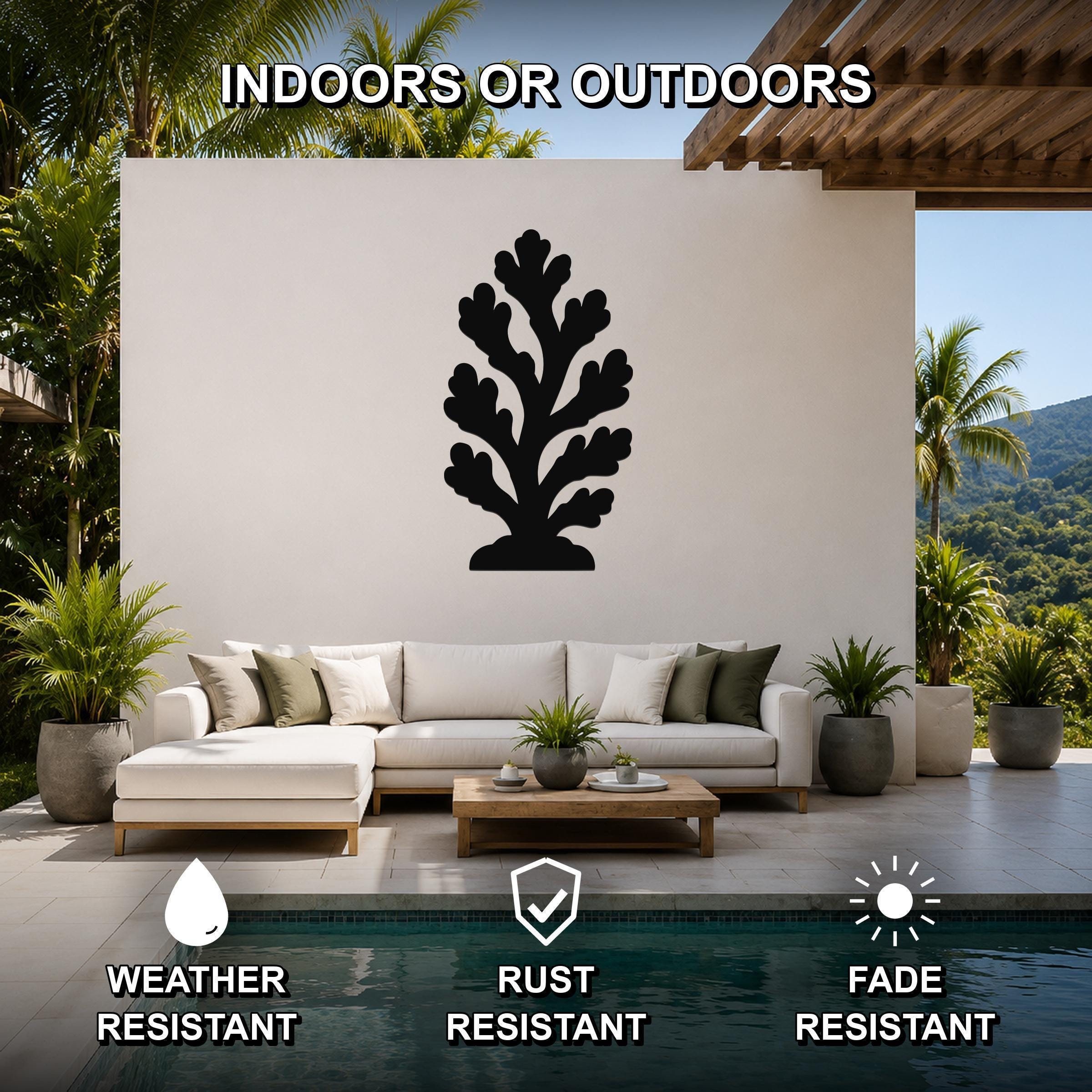 Black metal coral wall art silhouette mounted on a white outdoor wall above a white sectional sofa in a patio setting.