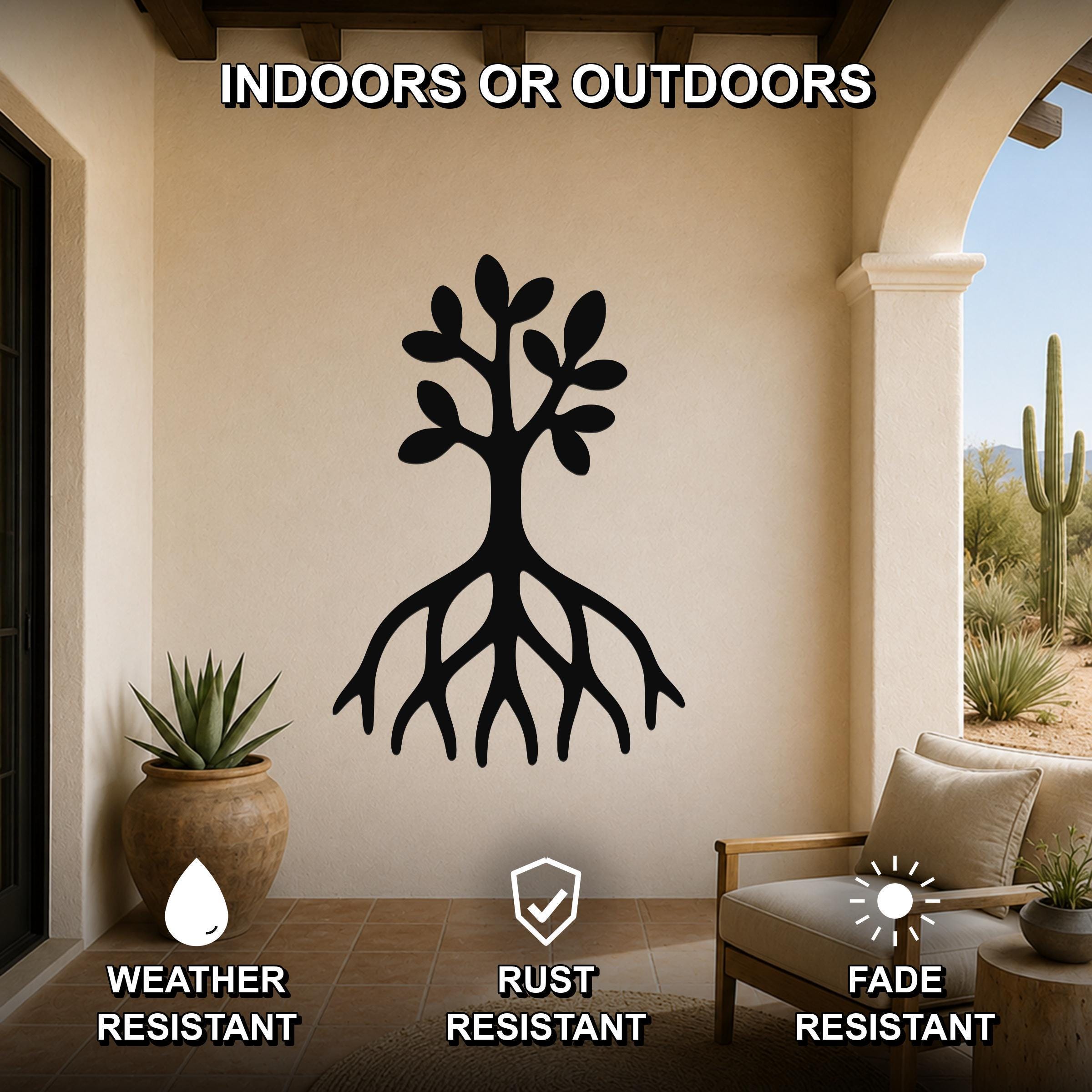 Black metal tree wall art with roots and leaves cutout, mounted on a beige outdoor patio wall above a chair and potted plant.