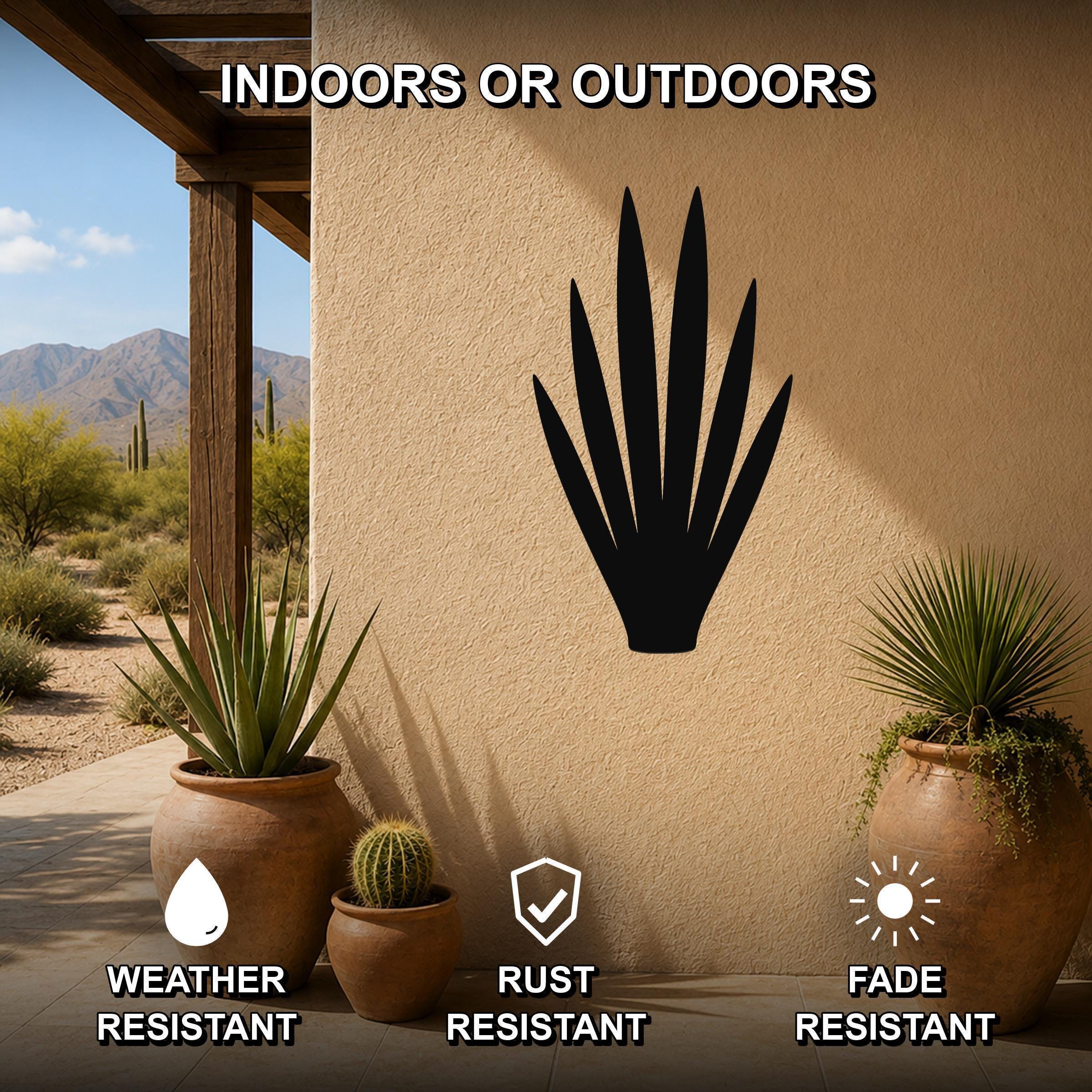 Black metal yucca wall art silhouette mounted on a beige outdoor wall, displayed on a patio with potted plants and desert scenery in the background.