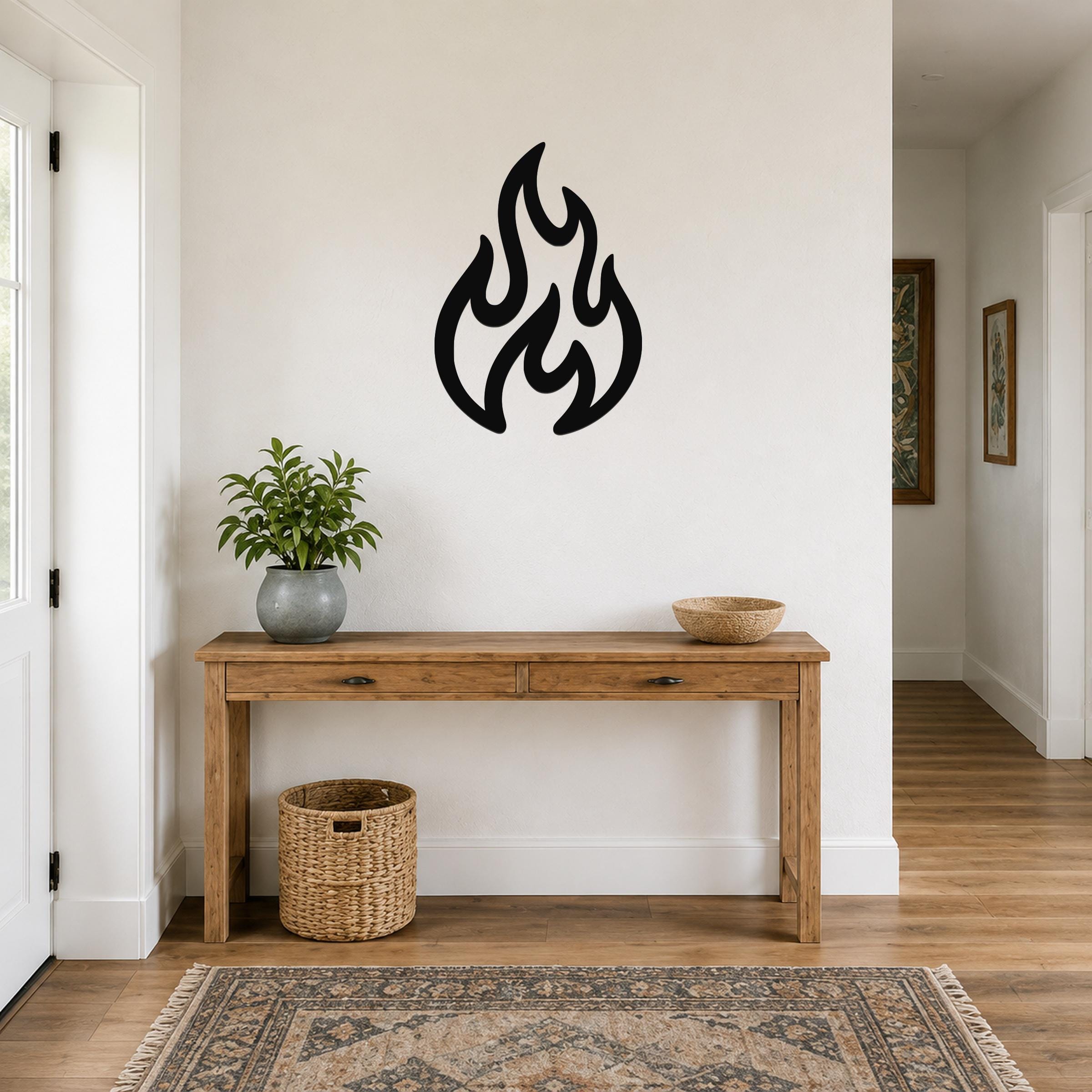 Black metal flame wall art with flowing, abstract cutout shapes, mounted on a white wall above a wooden console table in a hallway.