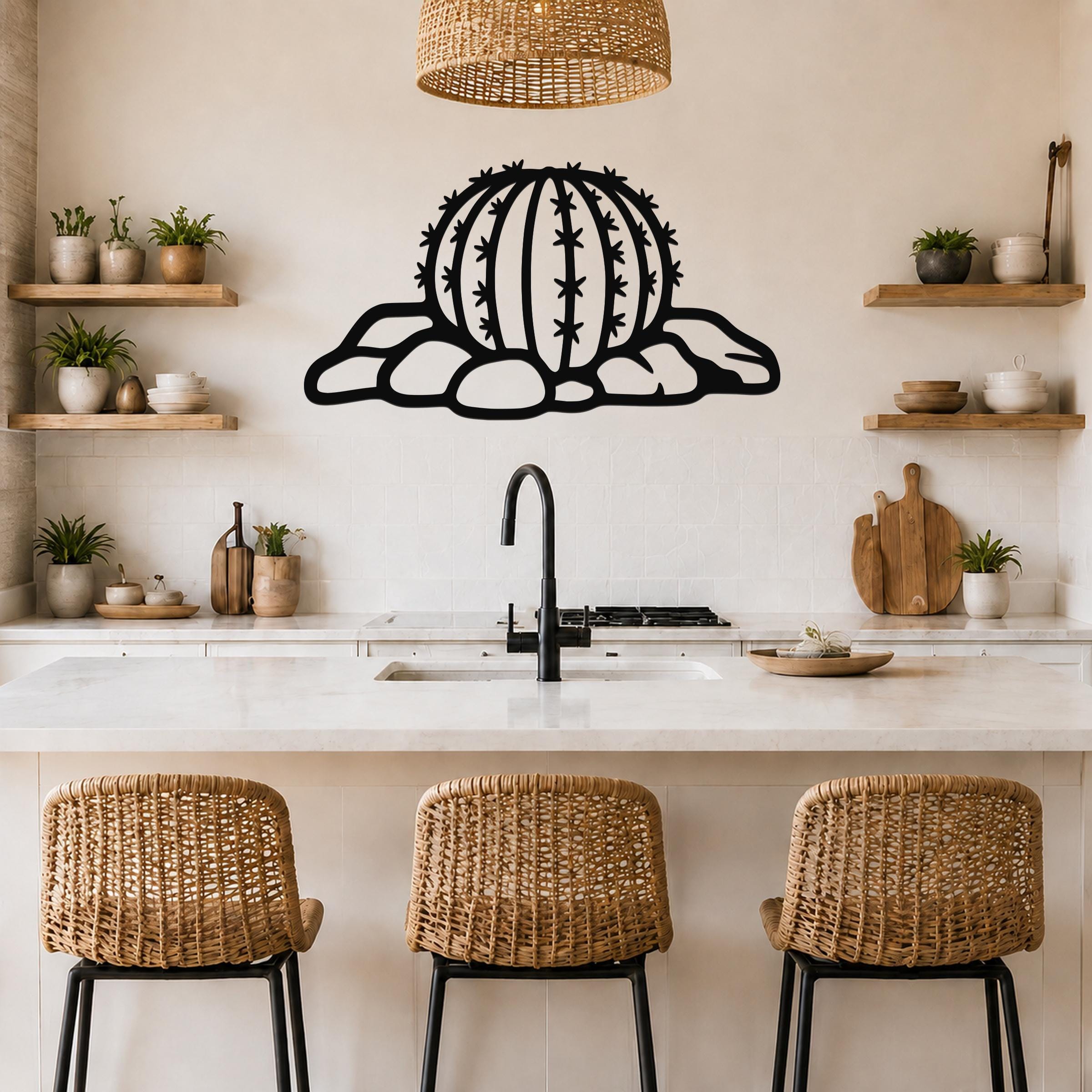 Black metal barrel cactus wall art with spines and rocks cutout, mounted on a kitchen wall above a counter.