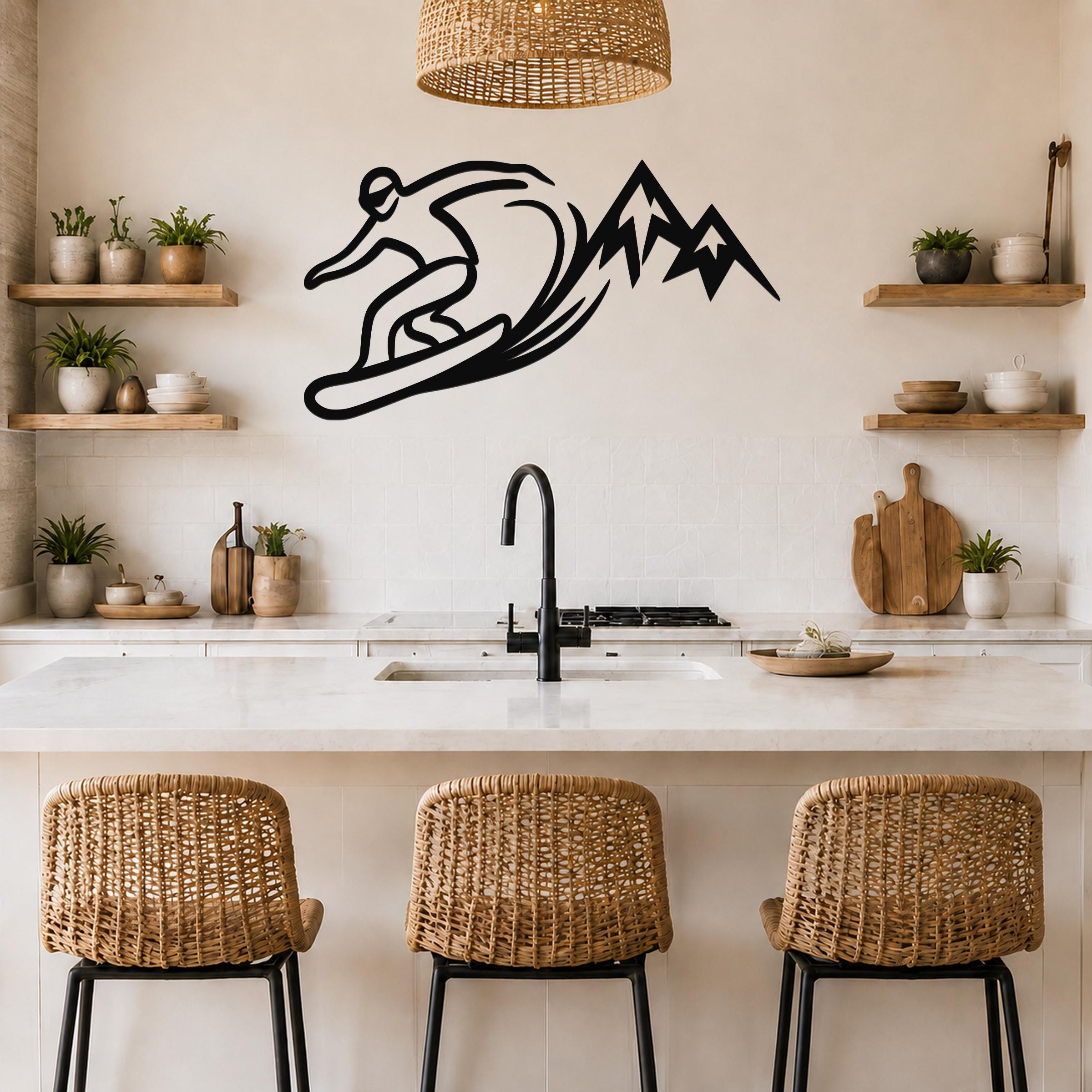 Black metal wall art silhouette of a snowboarder carving through powder with mountain peaks, mounted above a kitchen counter.