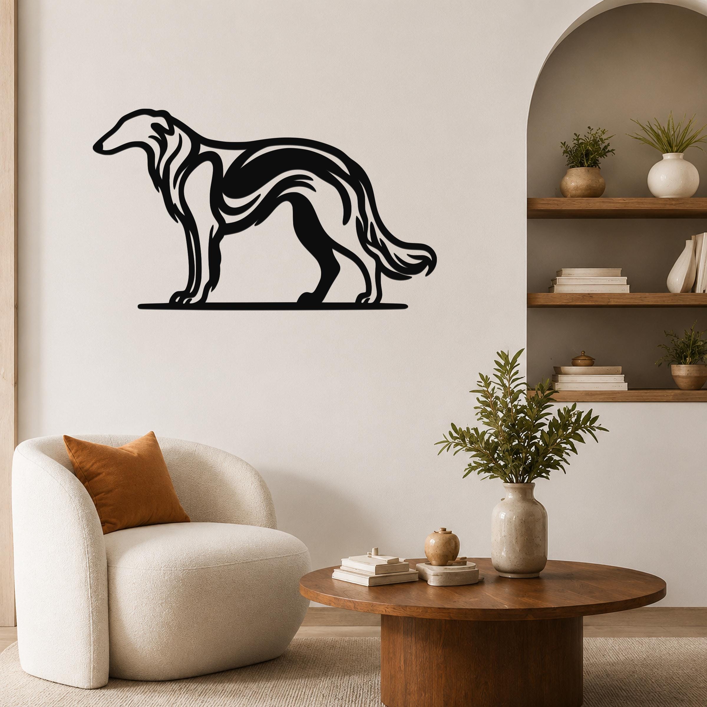 Black metal Borzoi dog wall art with flowing internal cutouts, mounted on a living room wall above a white armchair.