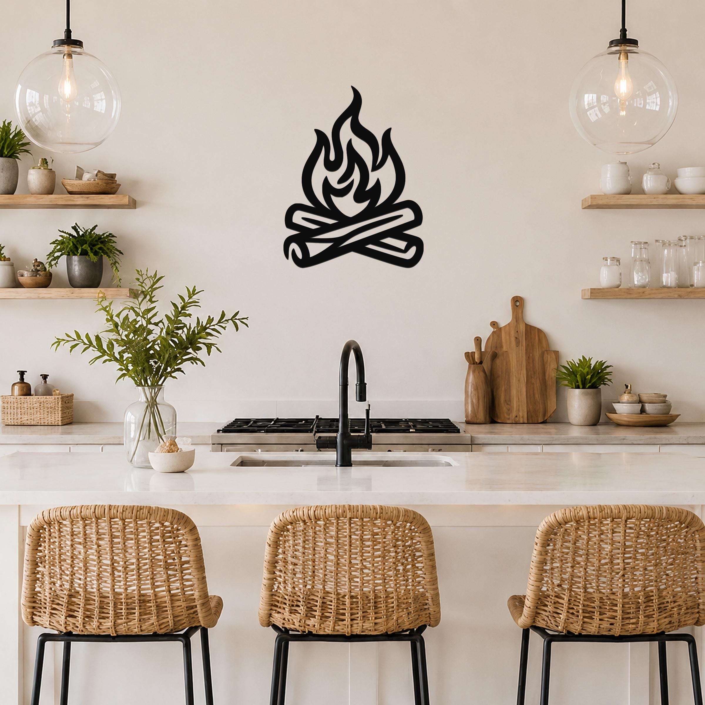 Black metal campfire wall art with flame and log silhouette, mounted on a kitchen wall above a counter.