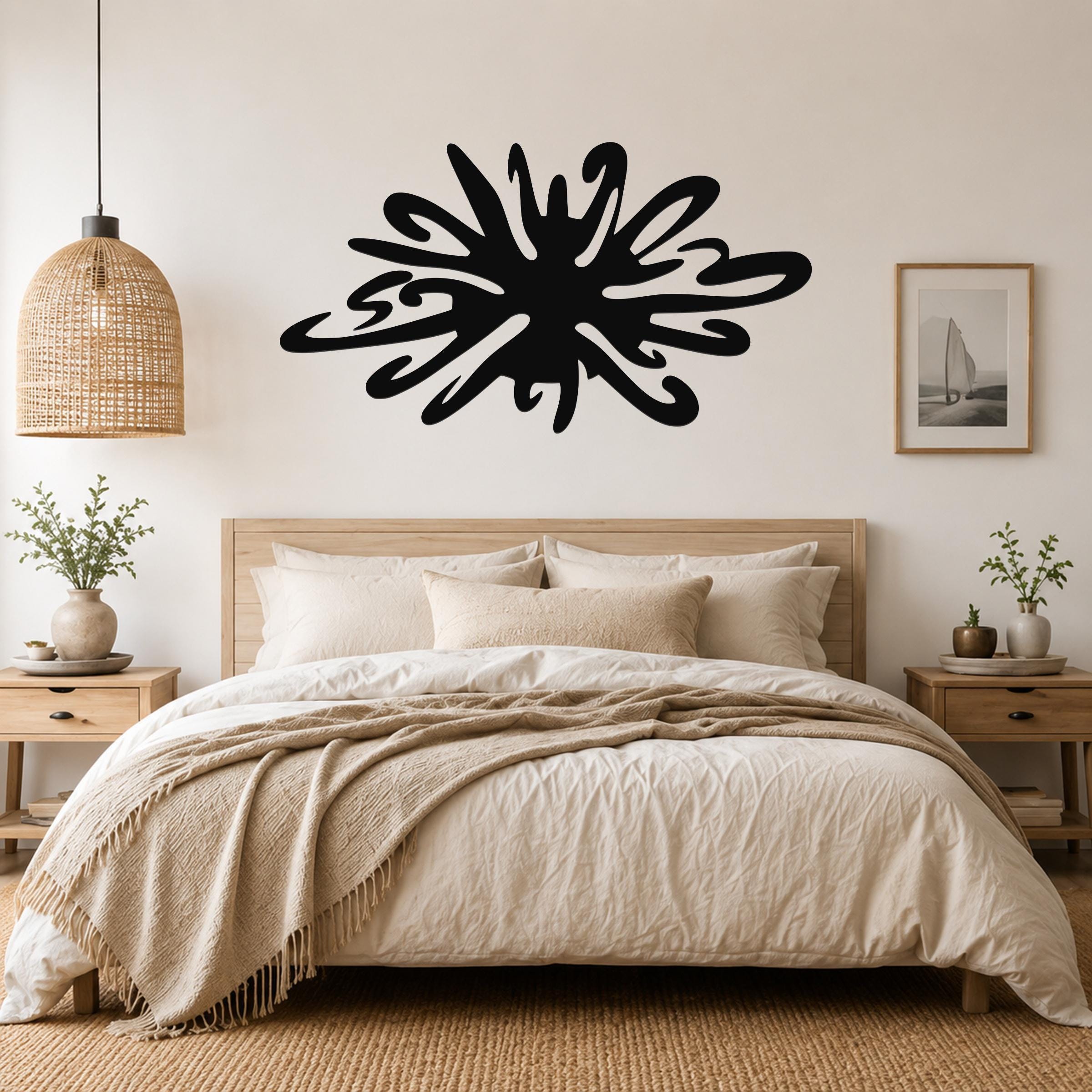 Black metal sea urchin wall art with organic spines and cutout details, mounted above a bed in a neutral bedroom.