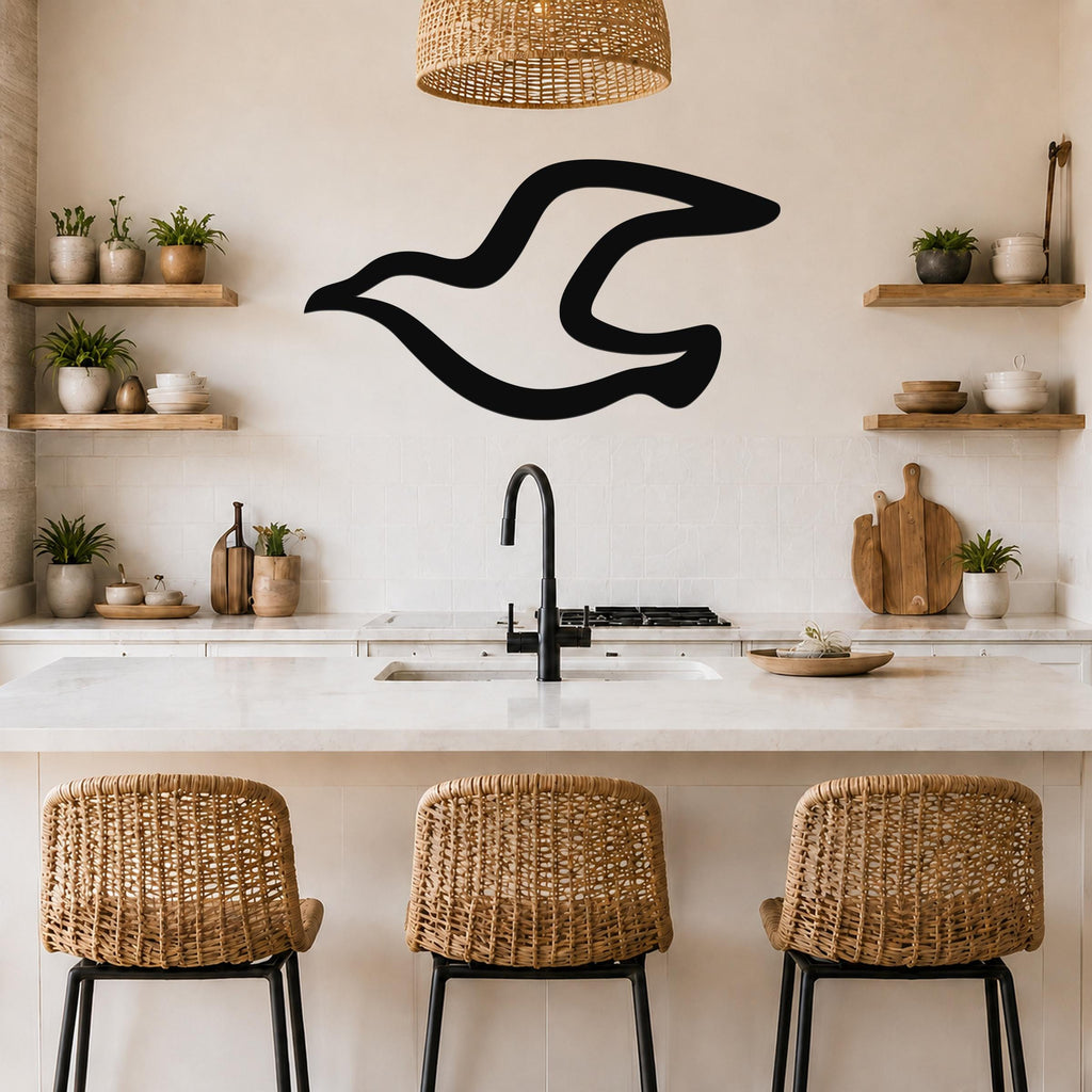 Black metal seagull wall art with a flowing silhouette, mounted on a kitchen wall above a counter.
