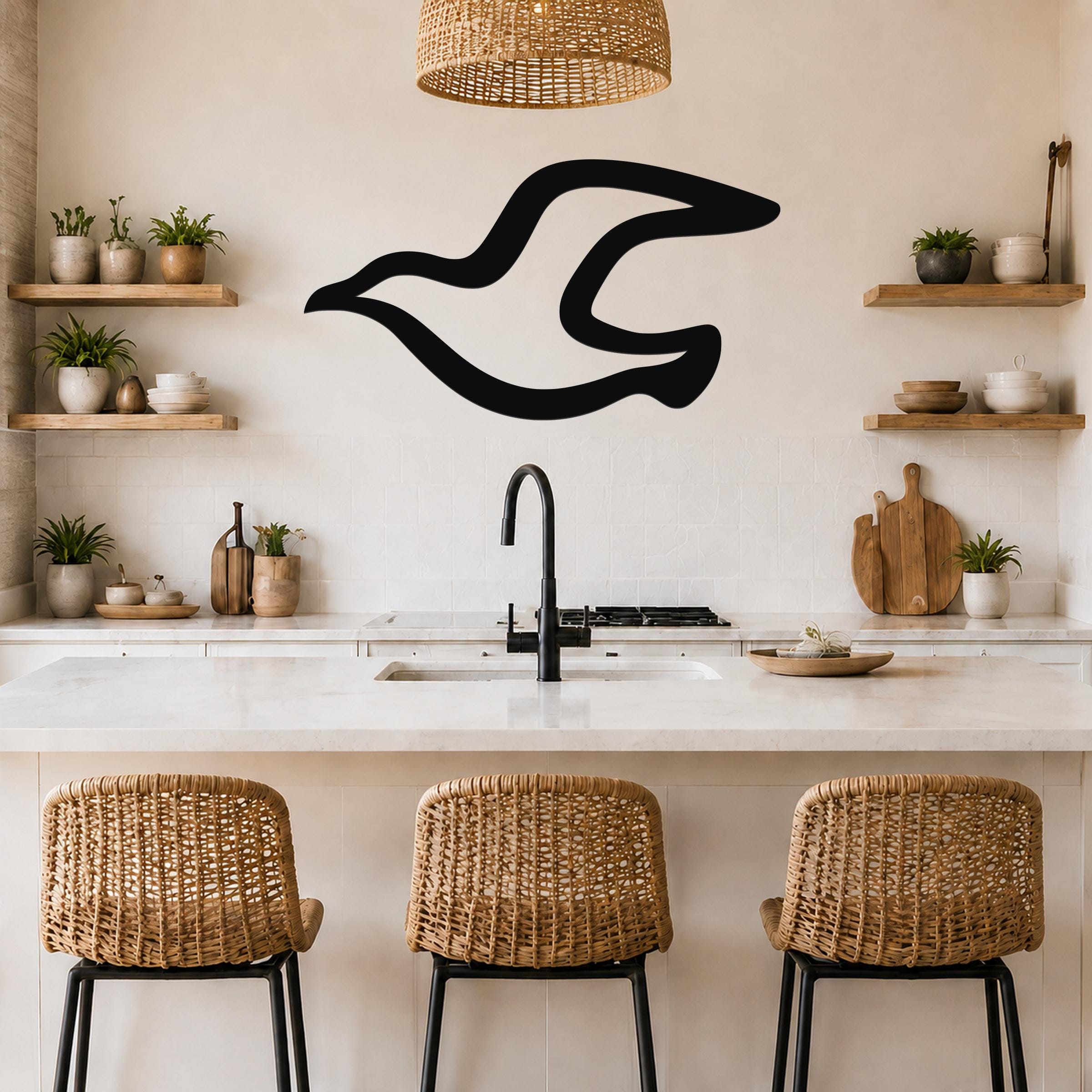 Black metal seagull wall art with a flowing silhouette, mounted on a kitchen wall above a counter.