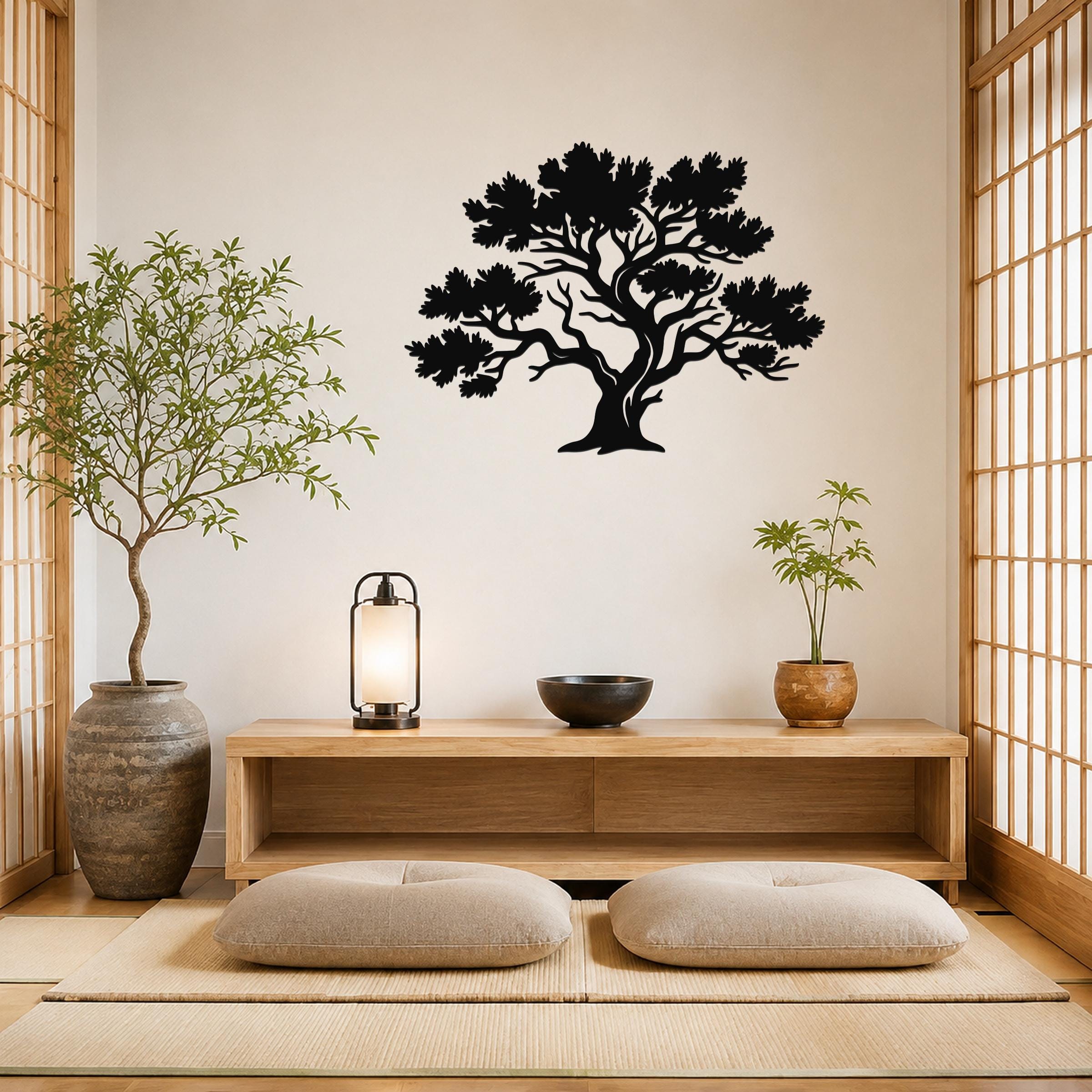 Black metal juniper tree wall art with detailed branch and leaf cutouts, mounted on a light-colored wall above a wooden console in a minimalist room.