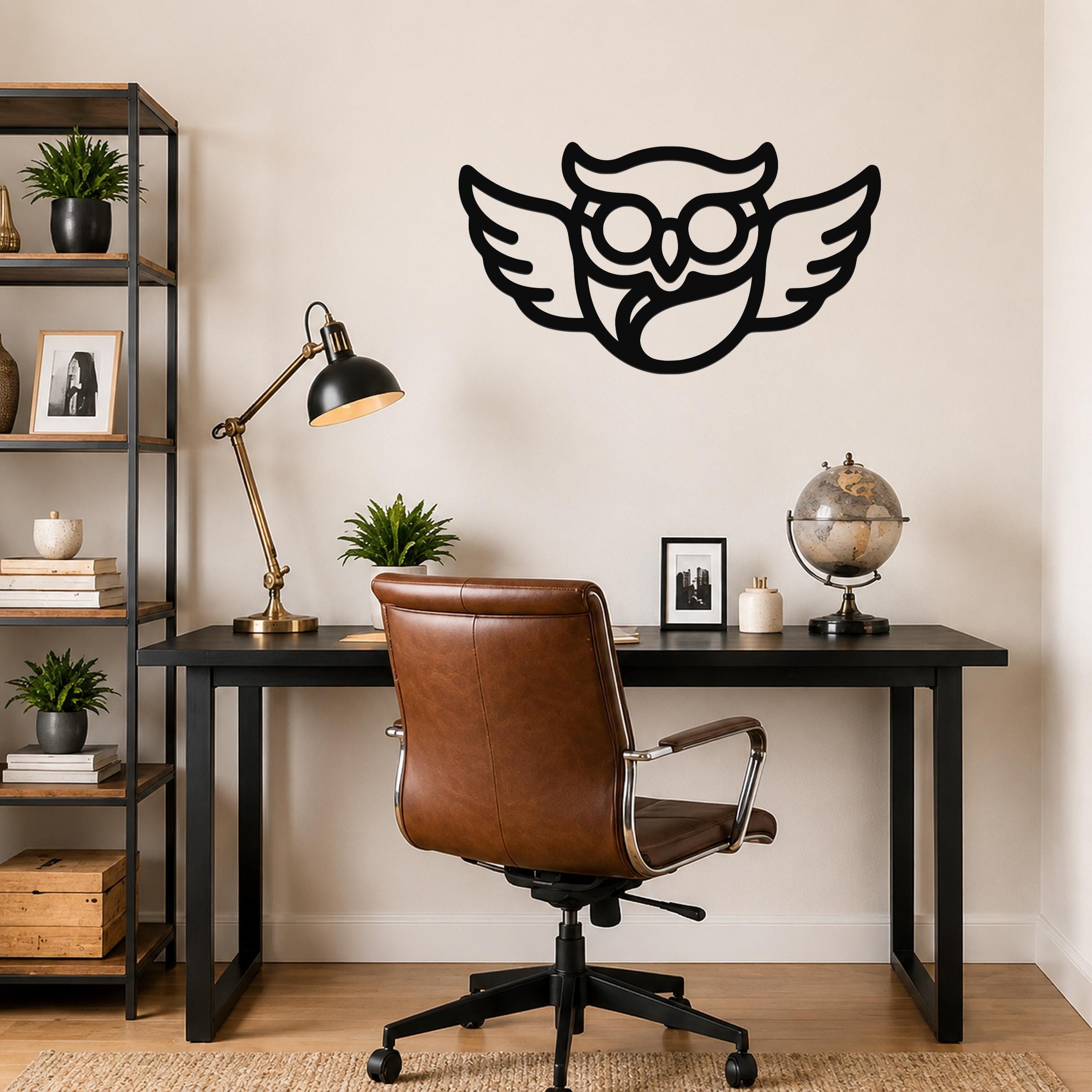 Black metal wall art featuring a silhouette of an owl with glasses and outstretched wings, mounted on a wall above a desk in a home office.