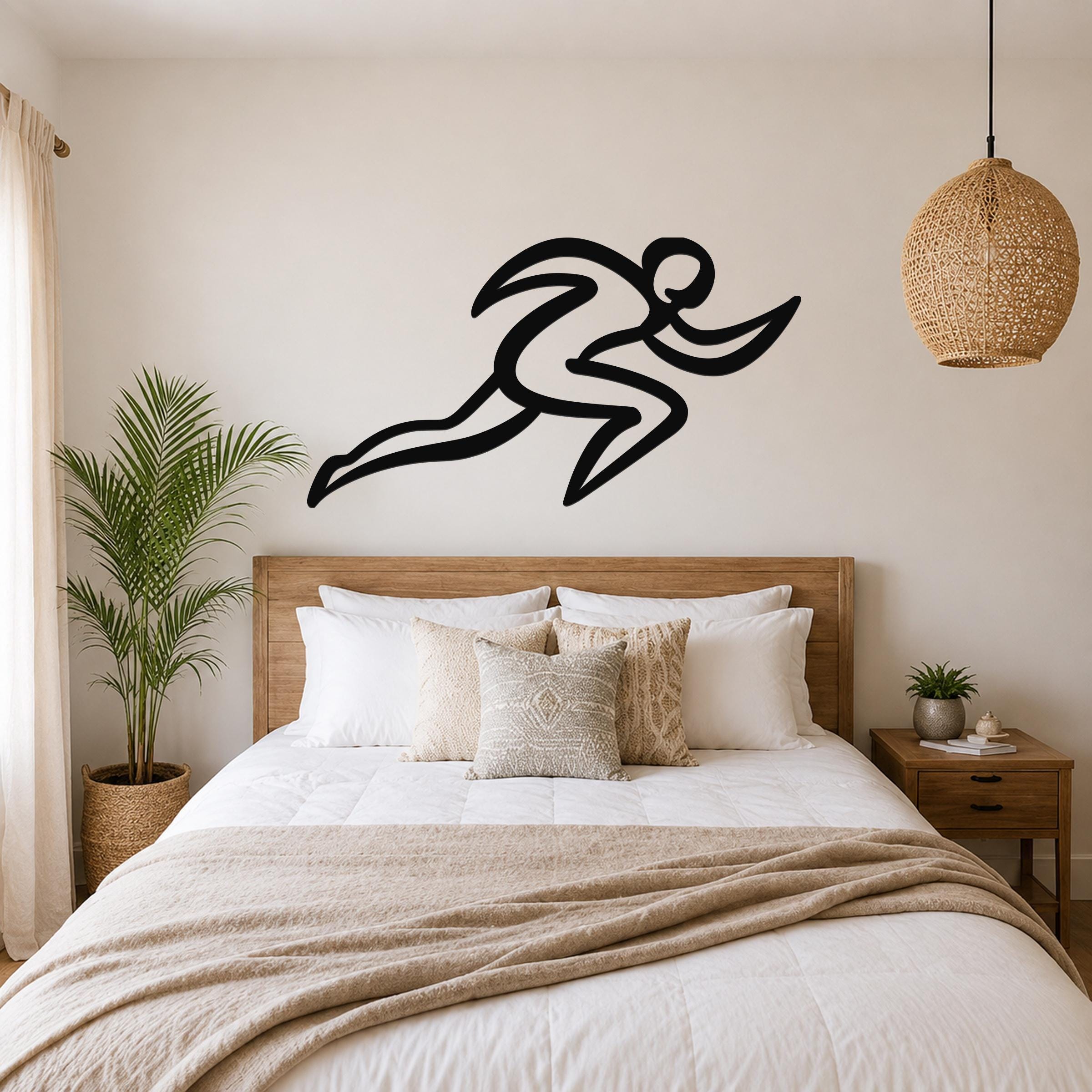 Black metal runner wall art with motion-line cutouts, mounted above a wooden bed in a neutral bedroom.
