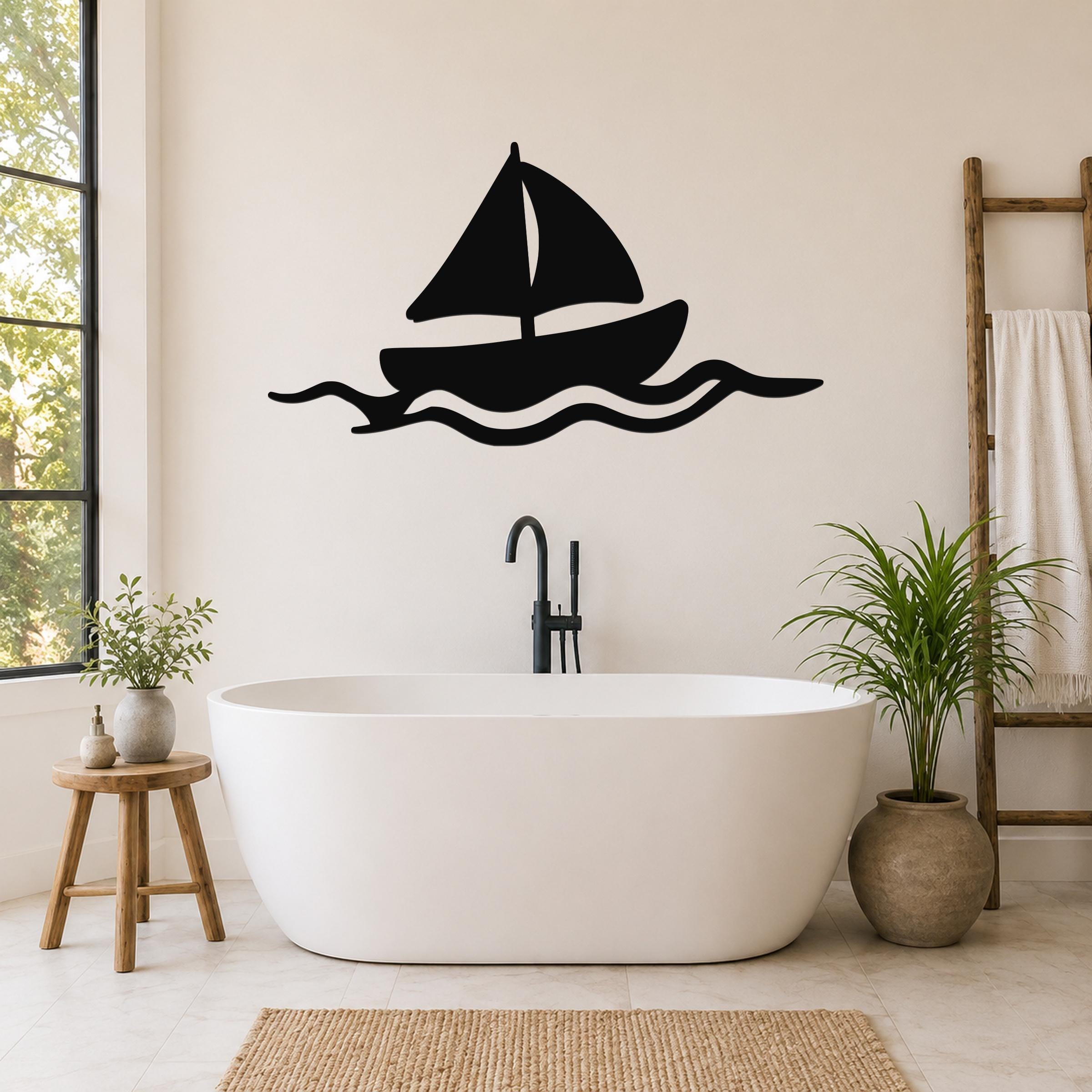 Black metal sailboat wall art with wave cutouts, mounted above a freestanding bathtub in a bright bathroom.