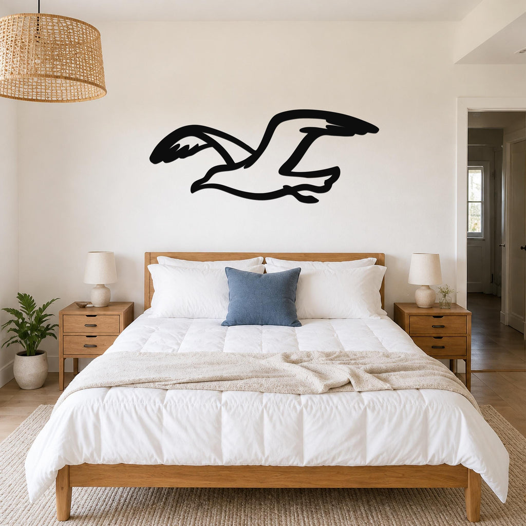 Black metal seagull wall art with motion-line cutouts, mounted above a wooden bed in a bright bedroom.