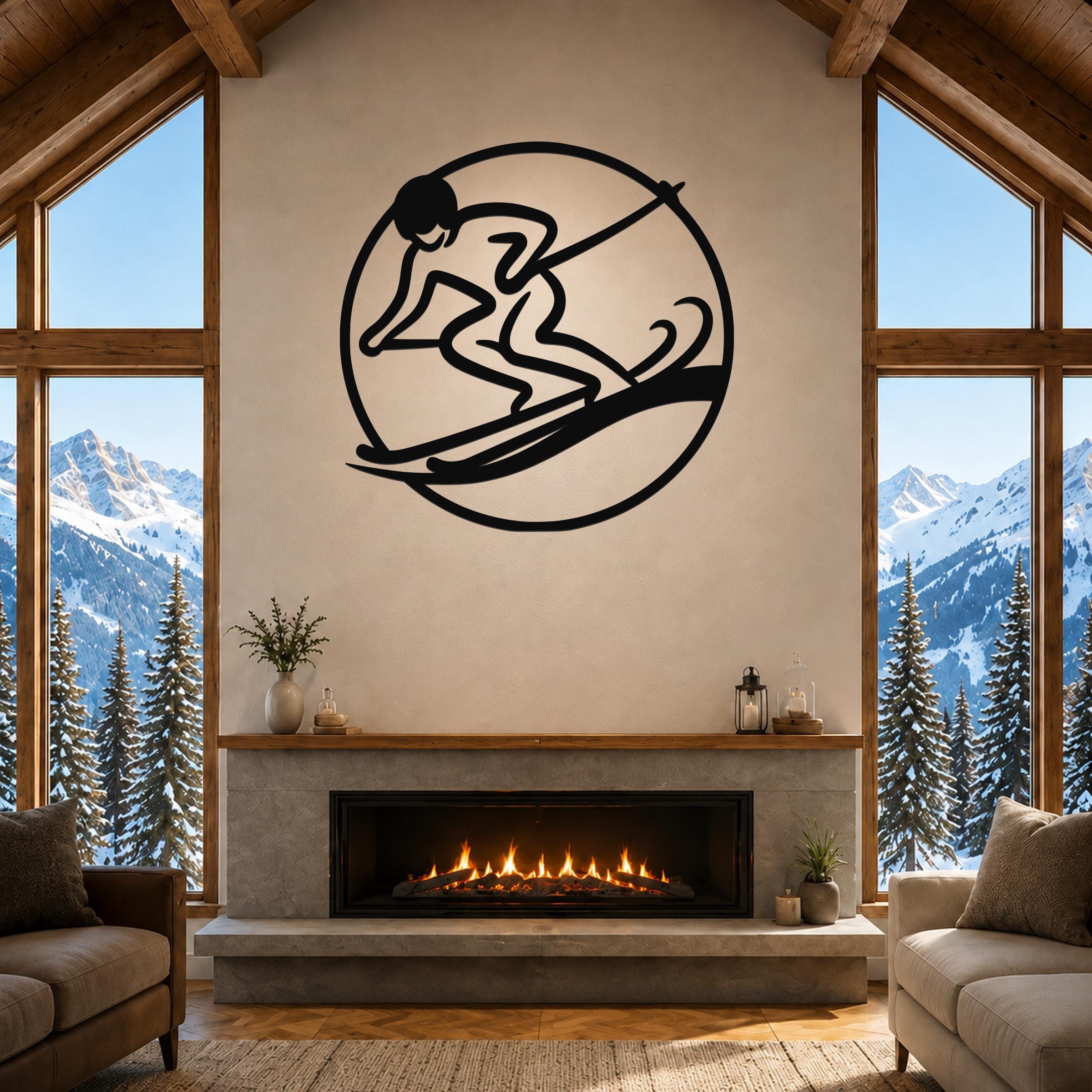 Black metal wall art of a skier silhouette inside a circle, mounted above a fireplace in a living room with large windows and snowy mountain views.