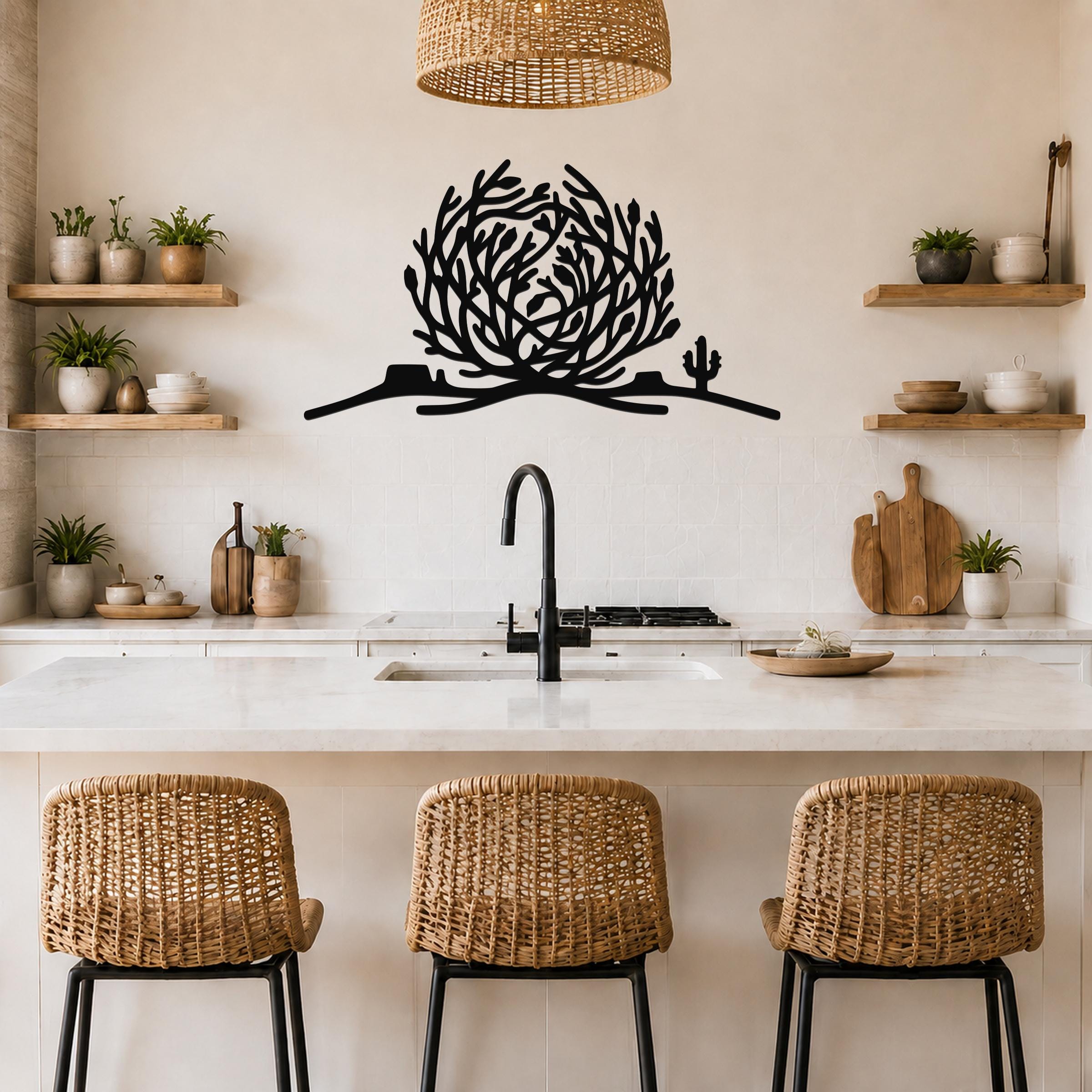 Black metal tumbleweed wall art with cactus silhouette, mounted above a kitchen counter in a neutral-toned kitchen.