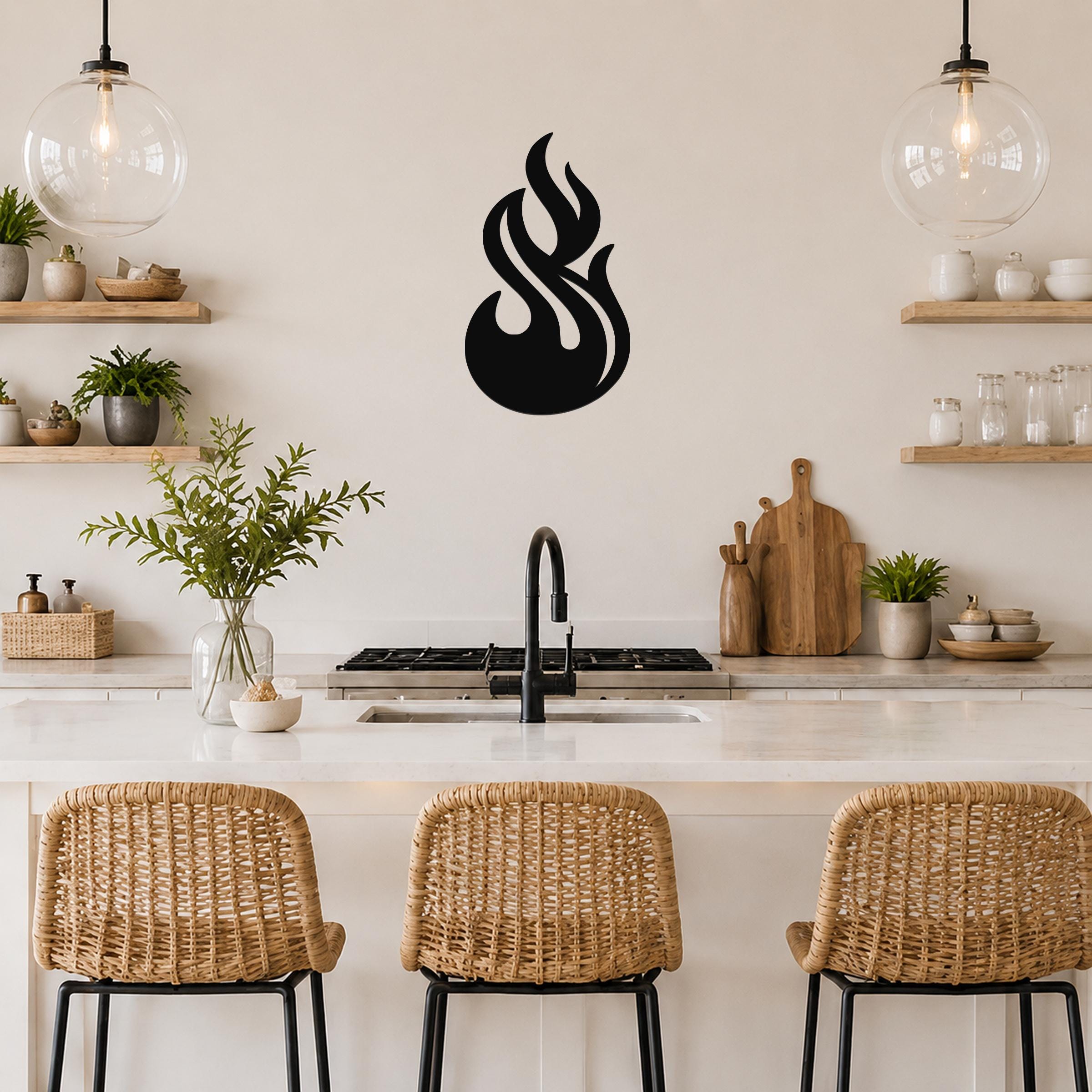Black metal flame wall art with fluid, swirling cutouts, mounted on a kitchen wall above a counter.